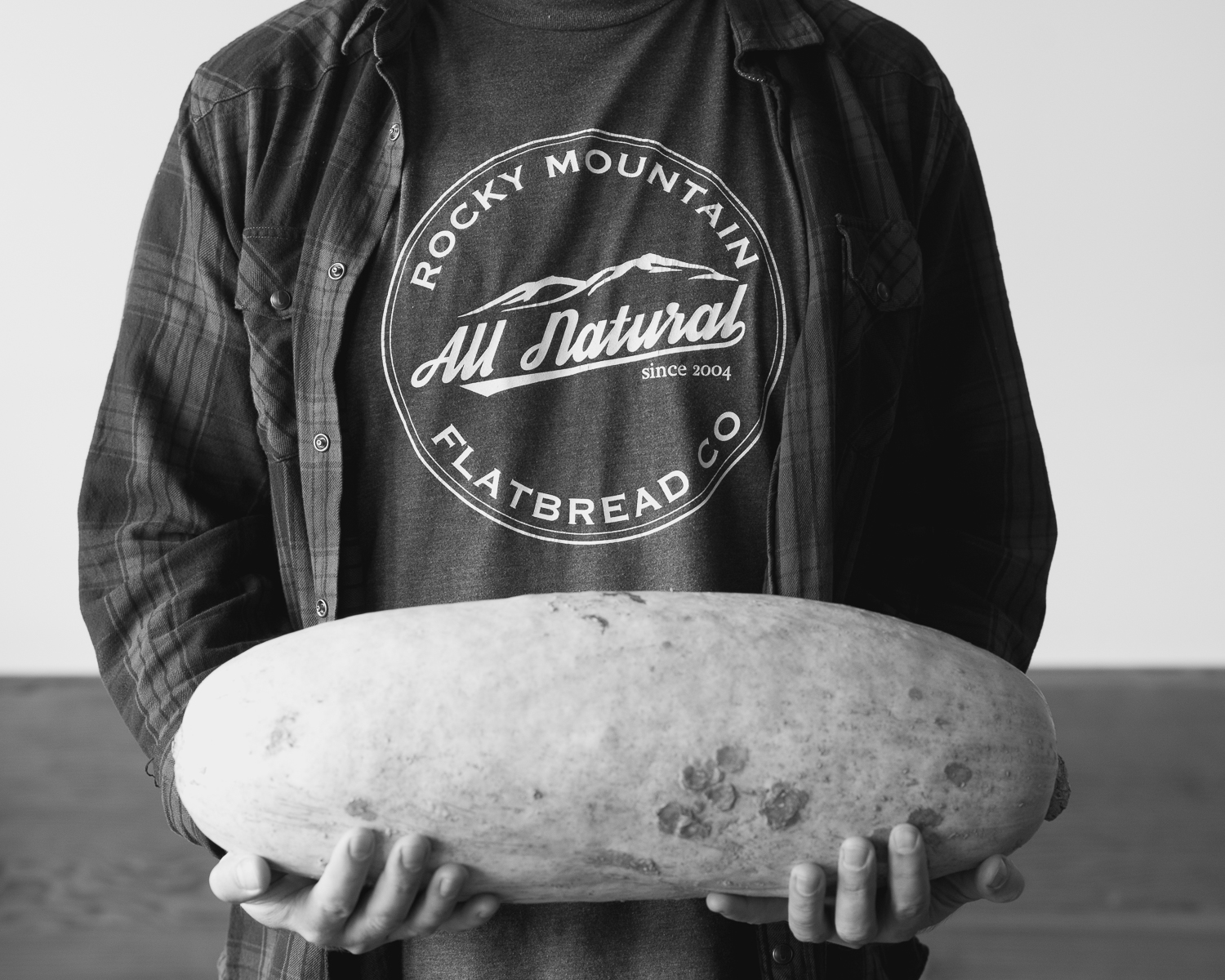 Man from rocky mountain flatbread holding large organic squash vancouver food photographer