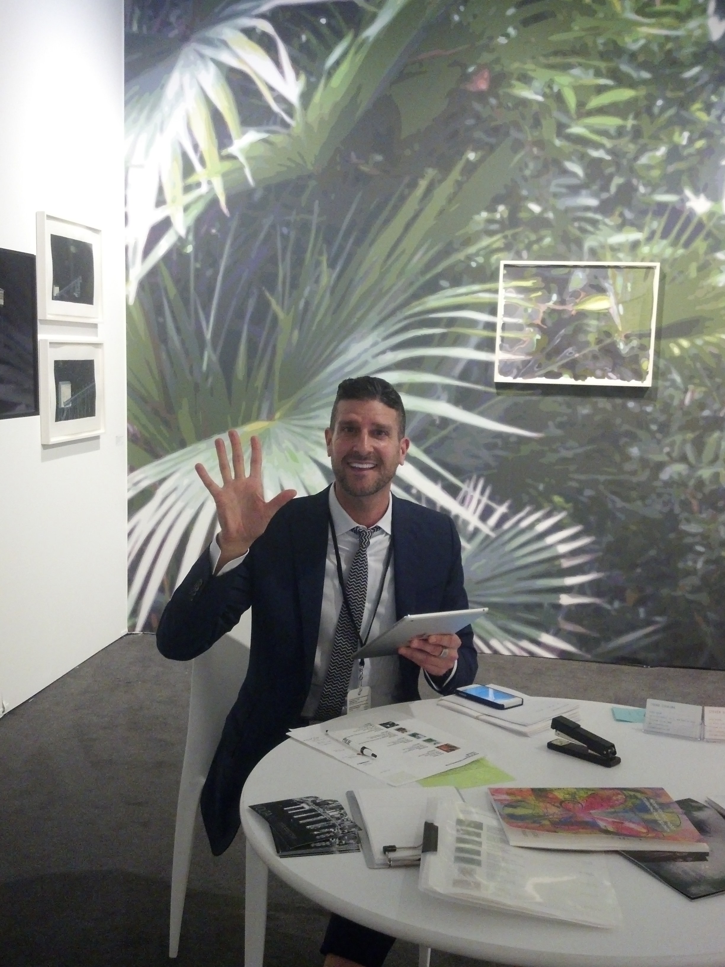 Steven Sergiovanni of Mixed Greens at work in his booth at PULSE Miami, featuring a wall installation by Naomi Reis. 