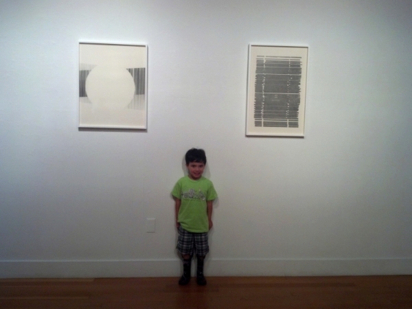 Wesley in between Claire Colette's graphite drawings at The Berkeley Art Center.