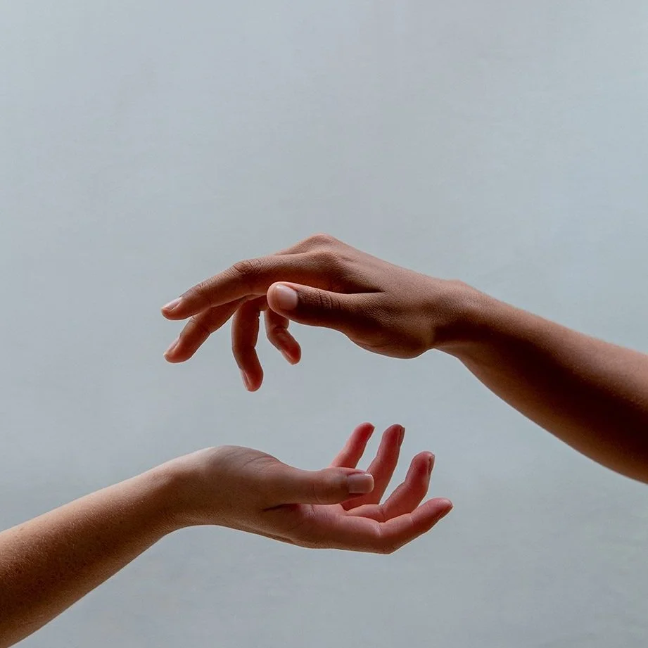 To hænder, en over og en under, nærkontakt mod hinanden, mod en neutral baggrund.