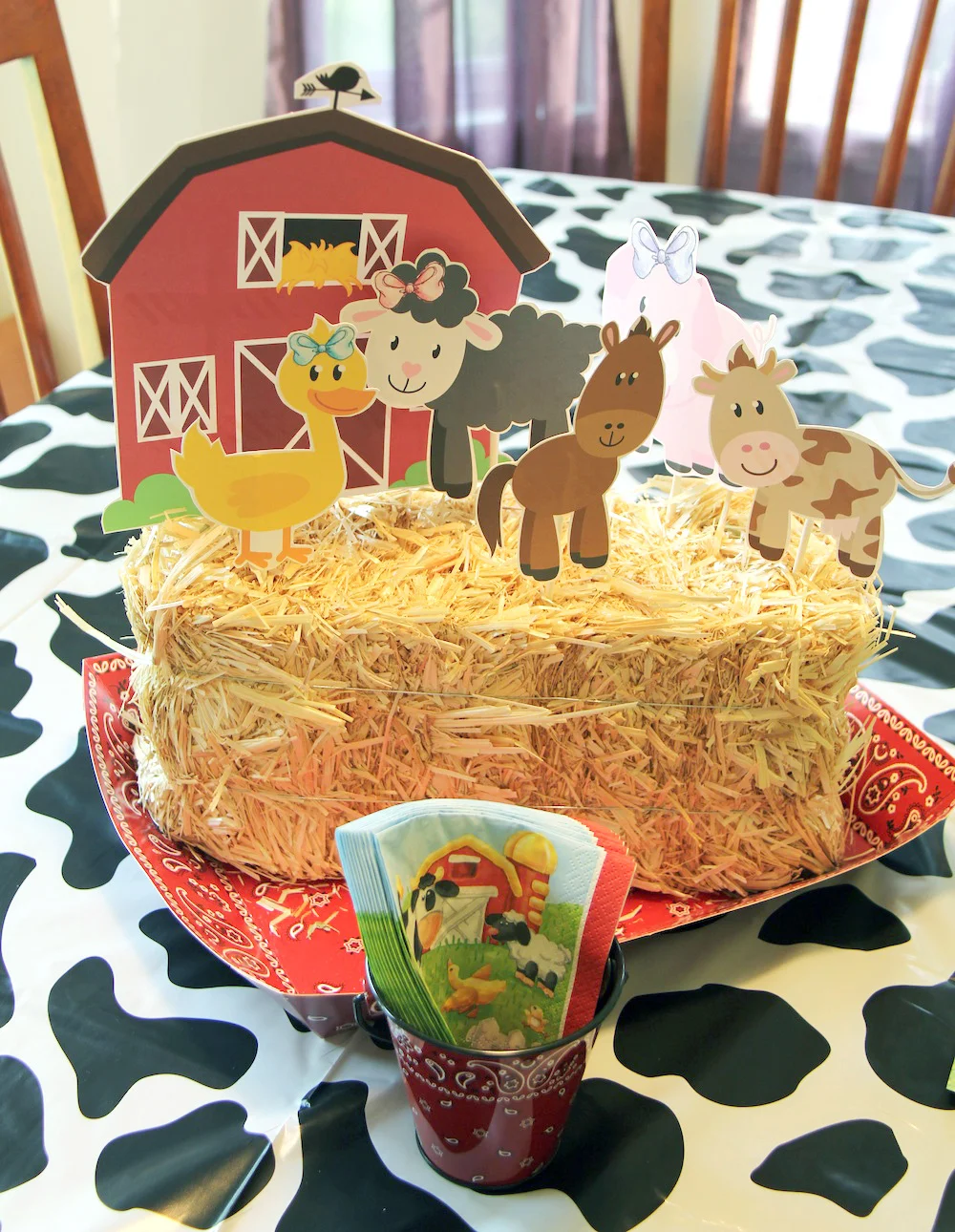 DIY Barn Themed Birthday Party Centerpiece | haybale with cut out farm animals | bandana and cow print patterns | as seen on www.gigglehearts.com