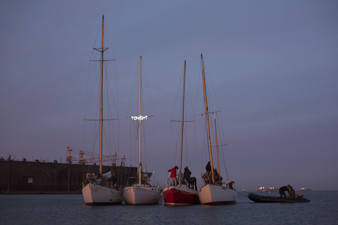 In June 2014 I opened a floating peepshow in the San Francisco Bay as part of the group exhibition Offshore-- commissioned by Southern Exposure. The project was specifically a response to the demise of two beloved clubs in the rapidly gentrifying San Francisco Bay Area: the Lusty Lady, the nation's only worker-owned and unionized strip club and Esta Noche, an infamous Latino gay bar which both closed within 6 months of each other. Because there didn’t seem to be enough affordable space on the landmass of San Francisco I decided to re-open some version of them on the water--to honor them as institutions of culture. One of the performers, a drag queen who came of age at Esta Noche, Persia, said that the whitewashing of San Francisco would turn Esta Noche into TONIGHT. So we named the floating island TONIGHT. Performers from the Lusty Lady, Esta Noche, and the Center for Sex and Culture danced inside the hulls of 4 sailboats rafted together offshore. More than 600 people were transported in small inflatable boats to the floating peepshow--- art people, old guys, queers, sex workers, young professionals, and working class sailors. It was many people’s first time either on the water or experiencing a peep show. 
