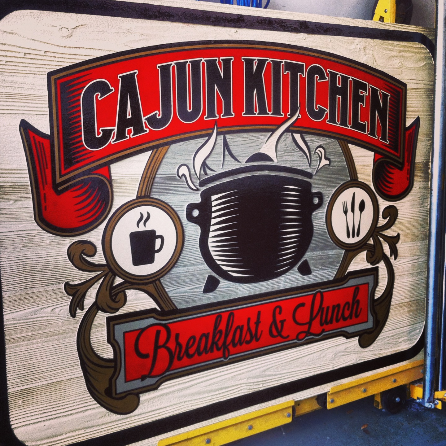 Exterior hand painted sign for CAJUN KITCHEN.