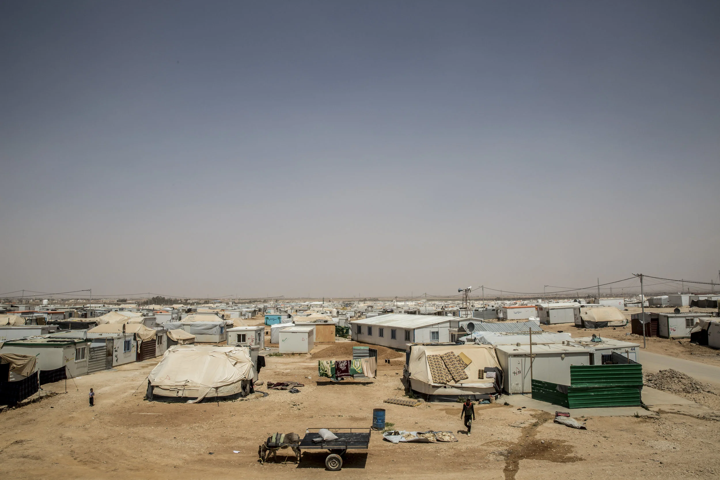Zaatari 04.06.2016 A higher vantage on daily life as seen from the top of a water tower — the highest point in Zaatari— an otherwise flat, barren landscape covering three square miles in the Jordanian desert. First opened in July 2012 the camp was initially designed to host a maximum of 60,000 inhabitants and began as a collection of tents in the desert; four years later it is now the 4th largest "city" in Jordan. The camp has grown into a settlement caravans and has earned the badge of being the world’s largest concentration of Syrian refugees — over half of which are children. In many ways the Zaatari camp has become a small, bustling, makeshift city with hospitals, schools, markets and Syrian men, women and children working each day to create something that resembles the life that they once had outside of the camp. Located just 13 km from the Syrian border, the camp is but a short drive from what is both a conflict zone and their (former) home.