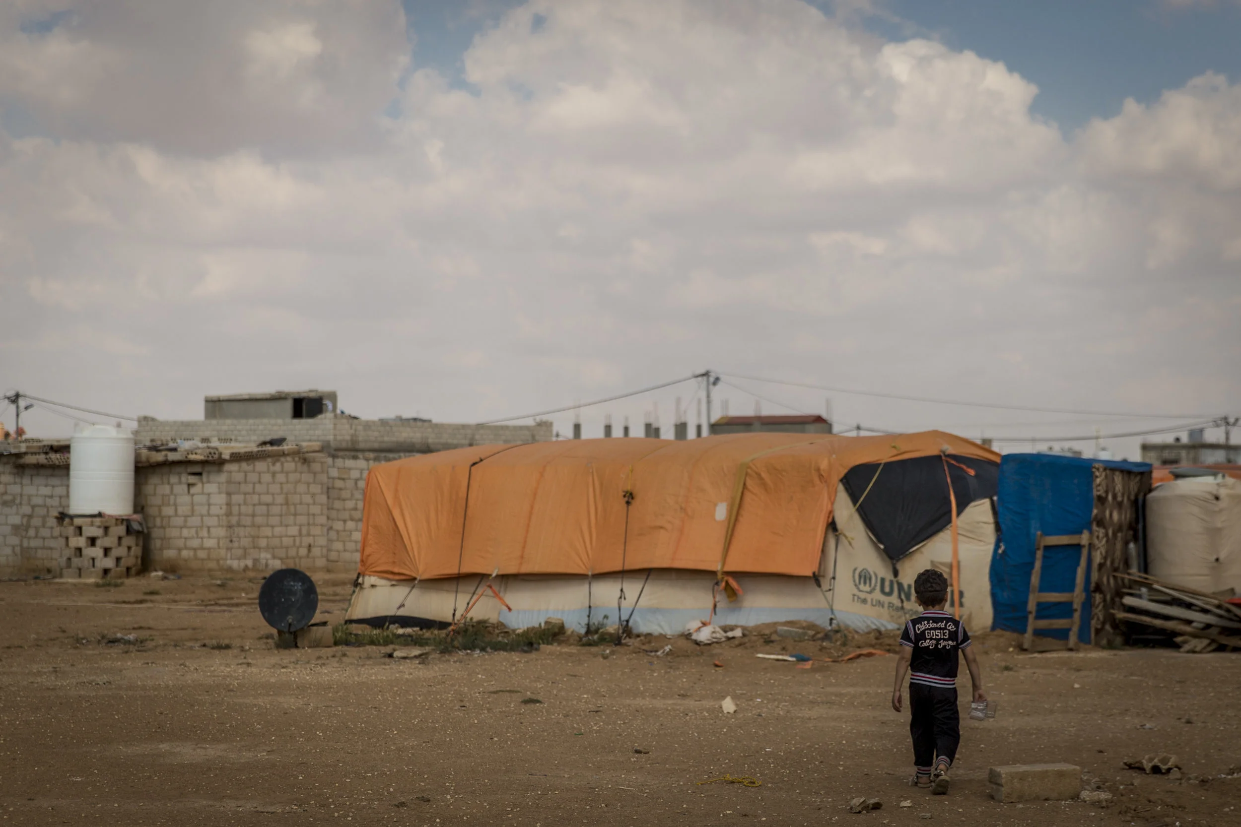 Halid walks “home” to his tent after running an errand for his father. When asked about his hopes for the future, Halid responded that he wants only for the fighting to stop so that he can go back to Syria, return to school and see his friends again.