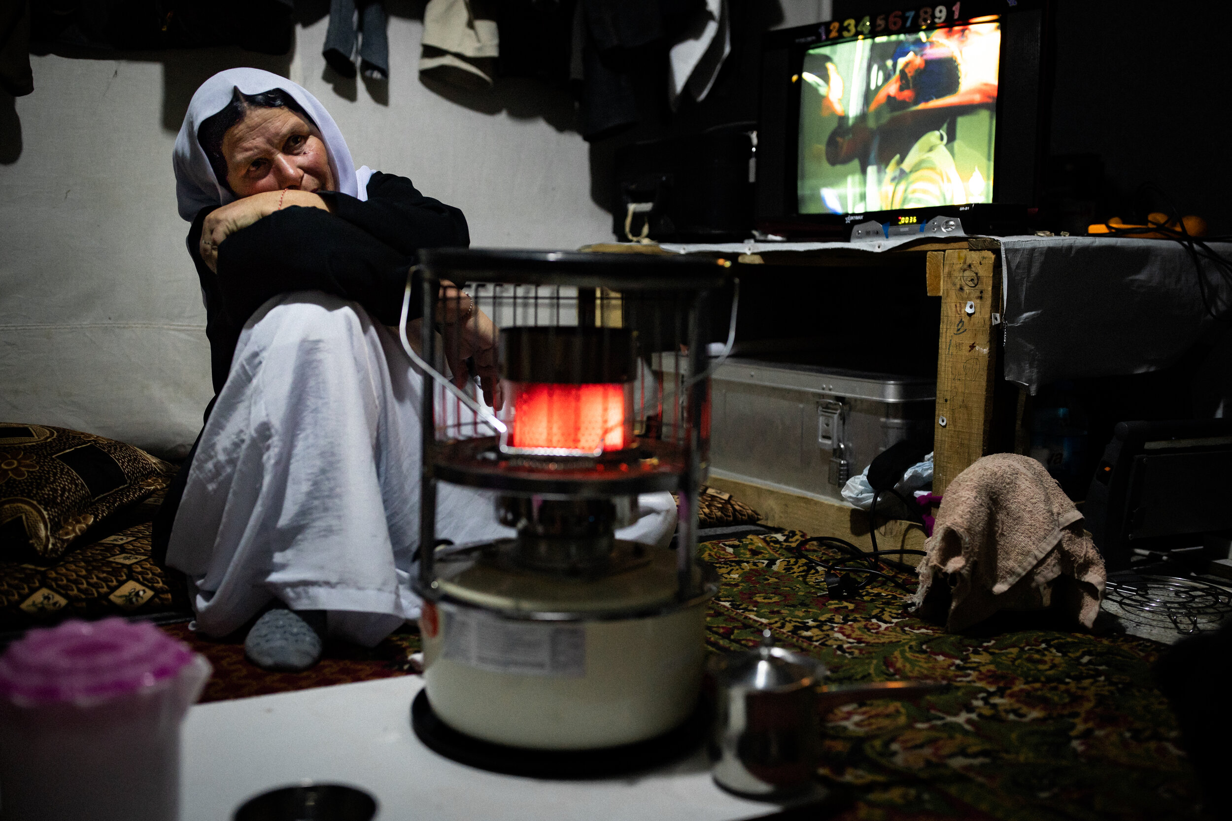 Samir uses a heating lamp to warm the inside of the tent she shares with her three children. The winter in the Bajad Kandala Yazidi Displacement Camp brings temperatures well below freezing. During the August 2014 ISIS attack Samir and her children were able to escape but her husband and two brothers chose to stay and fight. Nearly five years later she has not heard from any of them and assumes they were killed or taken captive.