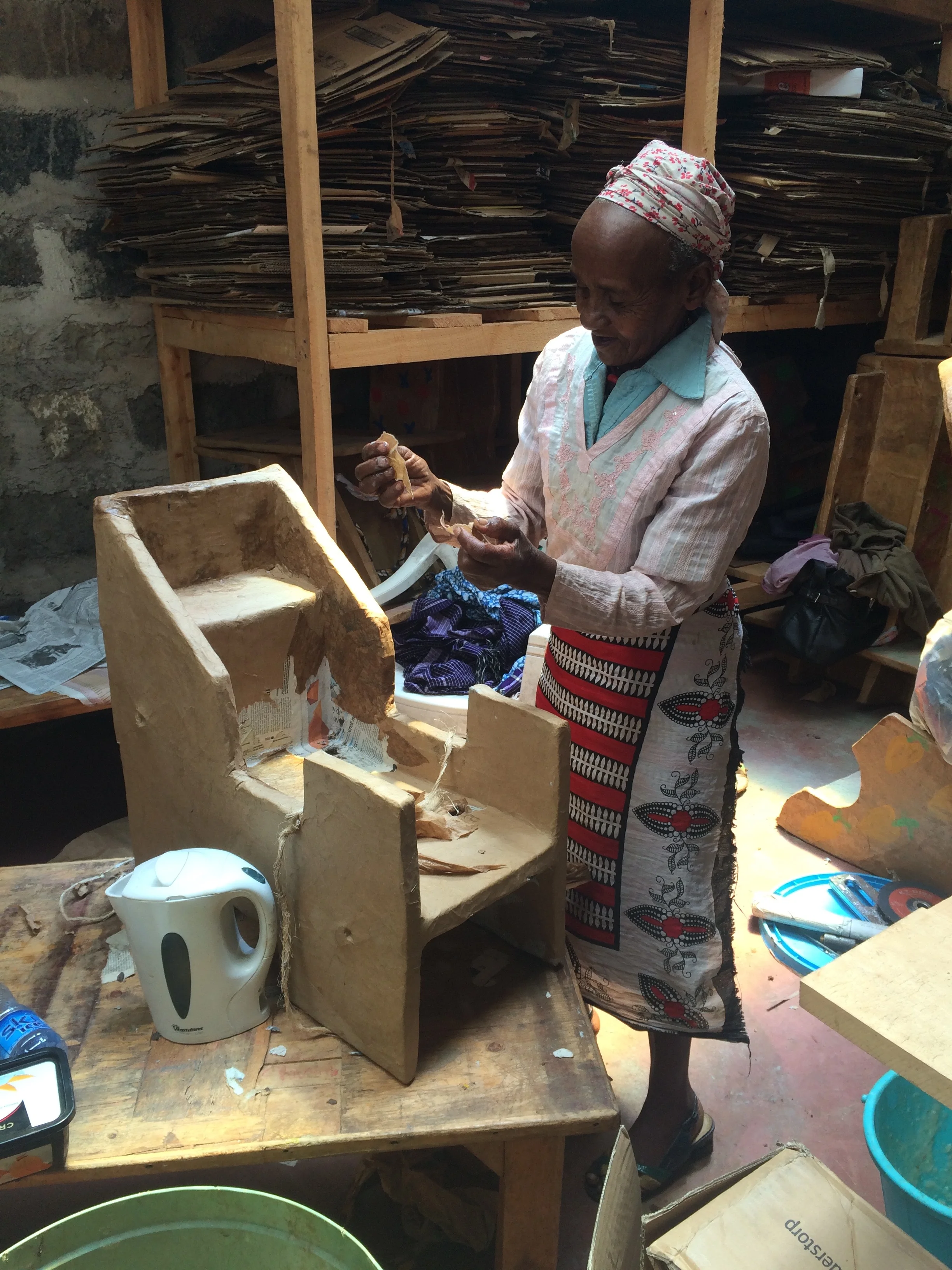 Granny Munene, who is employed at the SanctuaryArtists workshop, building one of the assistive cardboard chairs.