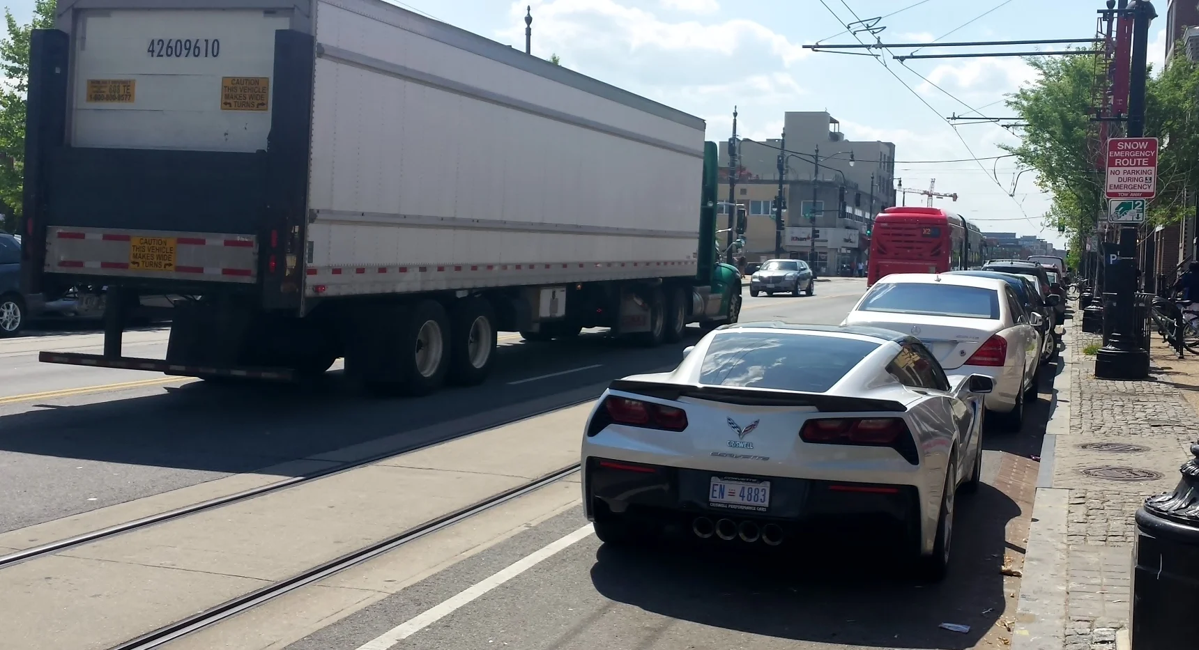 Quadruple threat: Big rig + streetcar tracks + parked cars + bus up ahead.