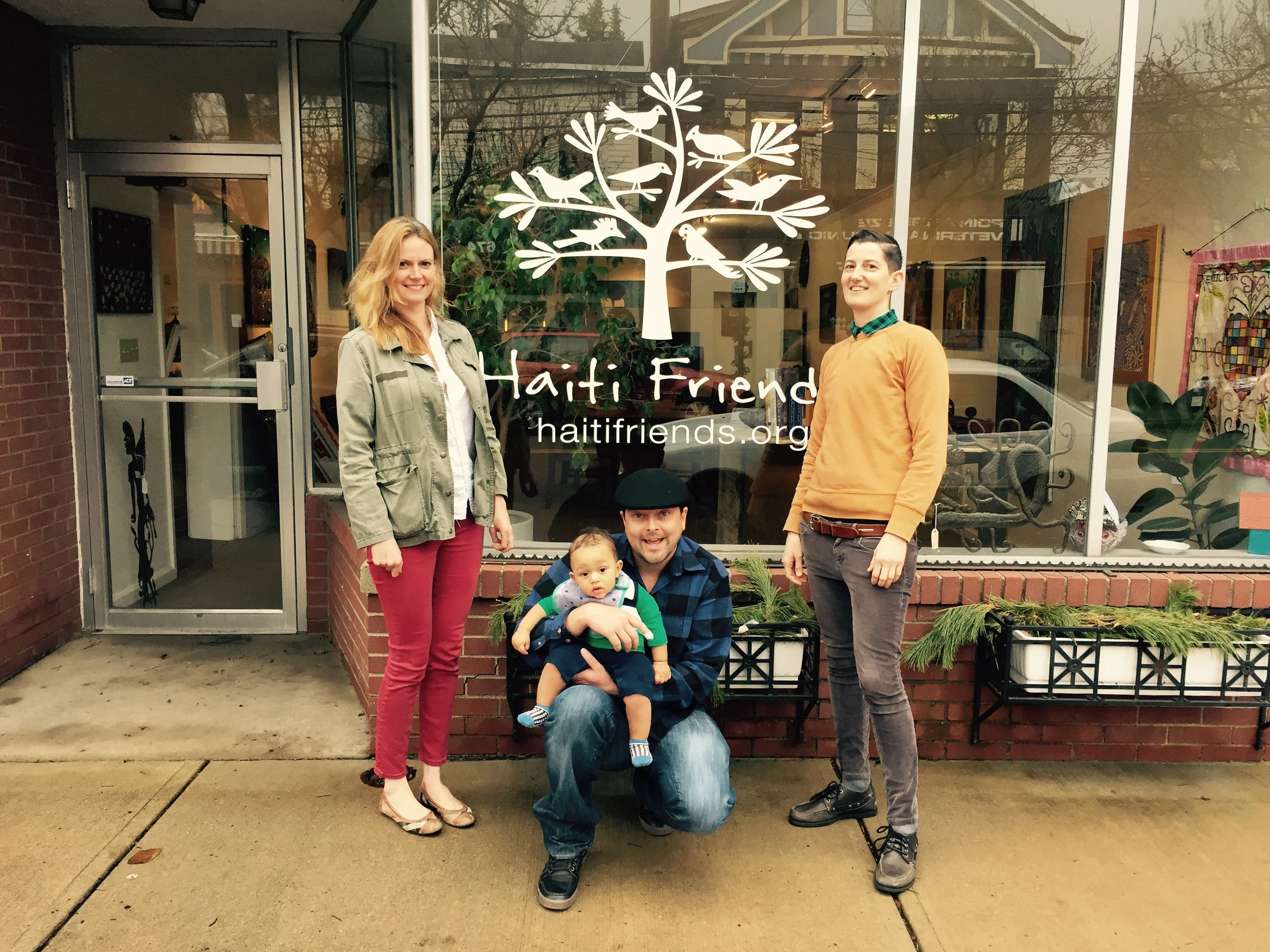 Deputy Director Bee (right), Program Associate Caitlin (left), and Executive Director Eddie with his son Olivier (center) in front of the new sign at the gallery on Reynolds St. 