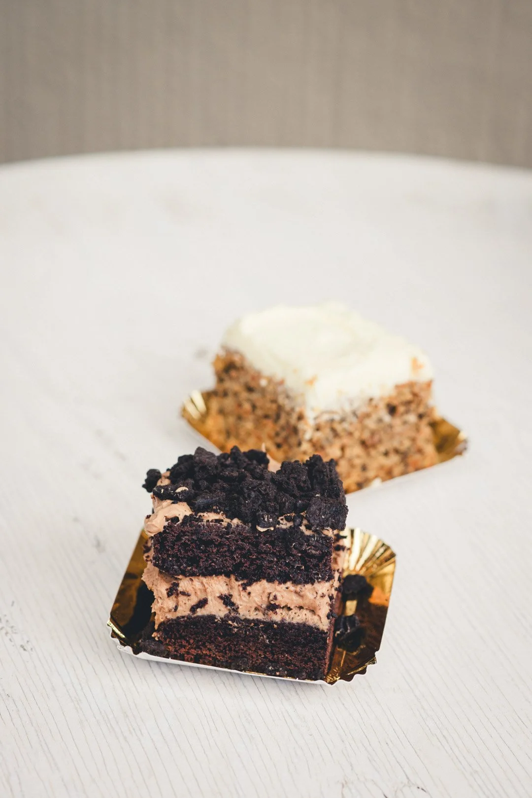 Zwei Kuchenstücke auf goldenen Tellerchen: Karottenkuchen mit Frosting und Schoko-Oreo-Torte mit Cremefüllung – Desserts Inc. beim Street Food Festival.