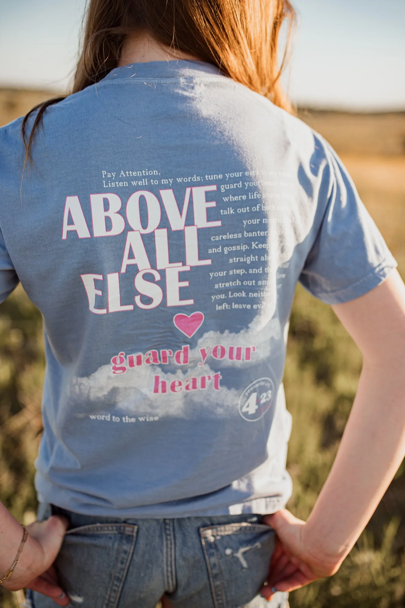 Christian comfort colors Above All else T-shirt inspired by bible verse proverbs 4:23.  blue denim tee with pink and white screen print reminding believers to guard your heart