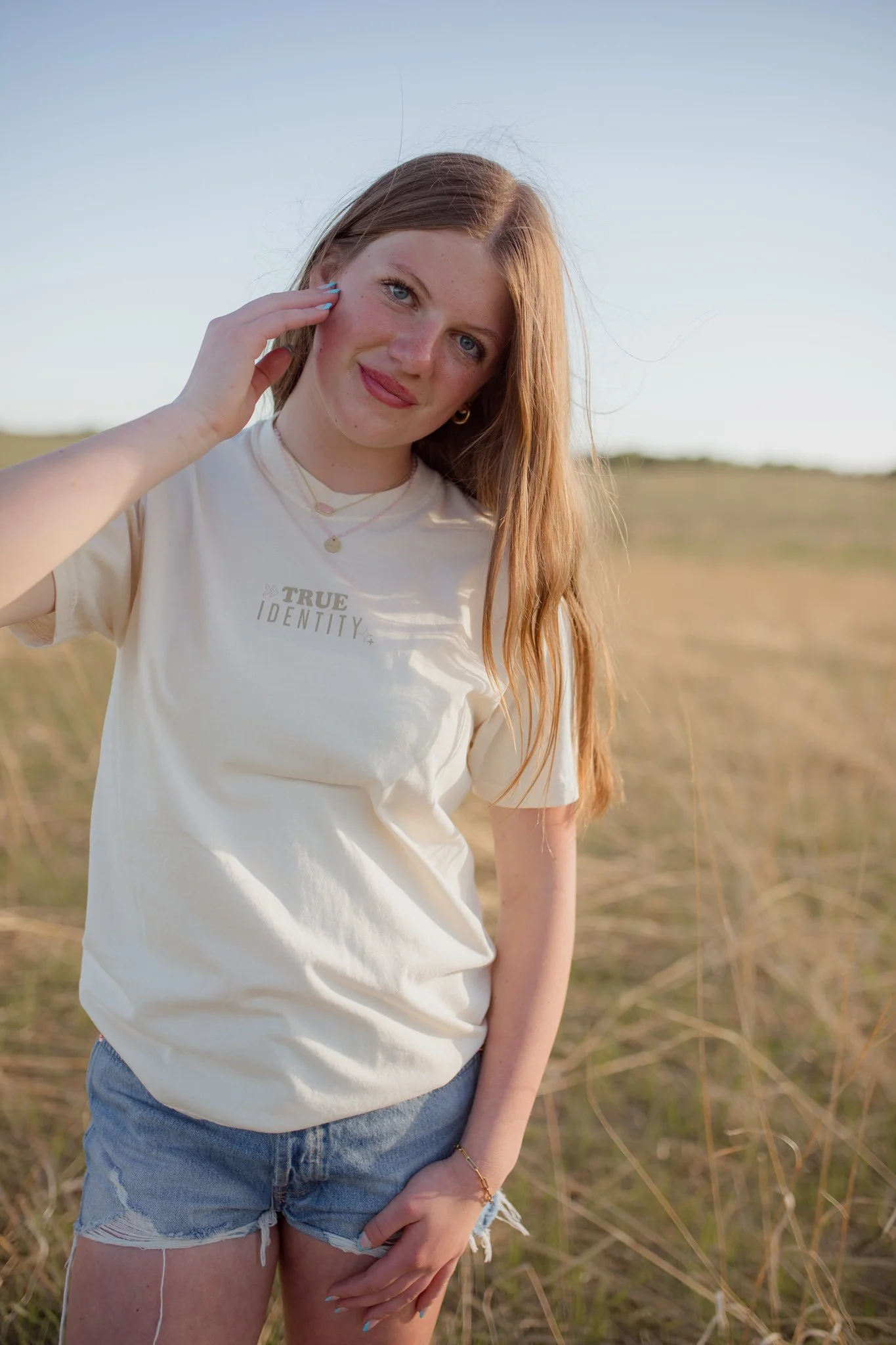 Christian comfort colors True Identity in Christ T-shirt inspired by bible verse Ephesians 1:3-8.  ivory tee with pink and tan screen print reminding believers that they are deeply chosen and loved.