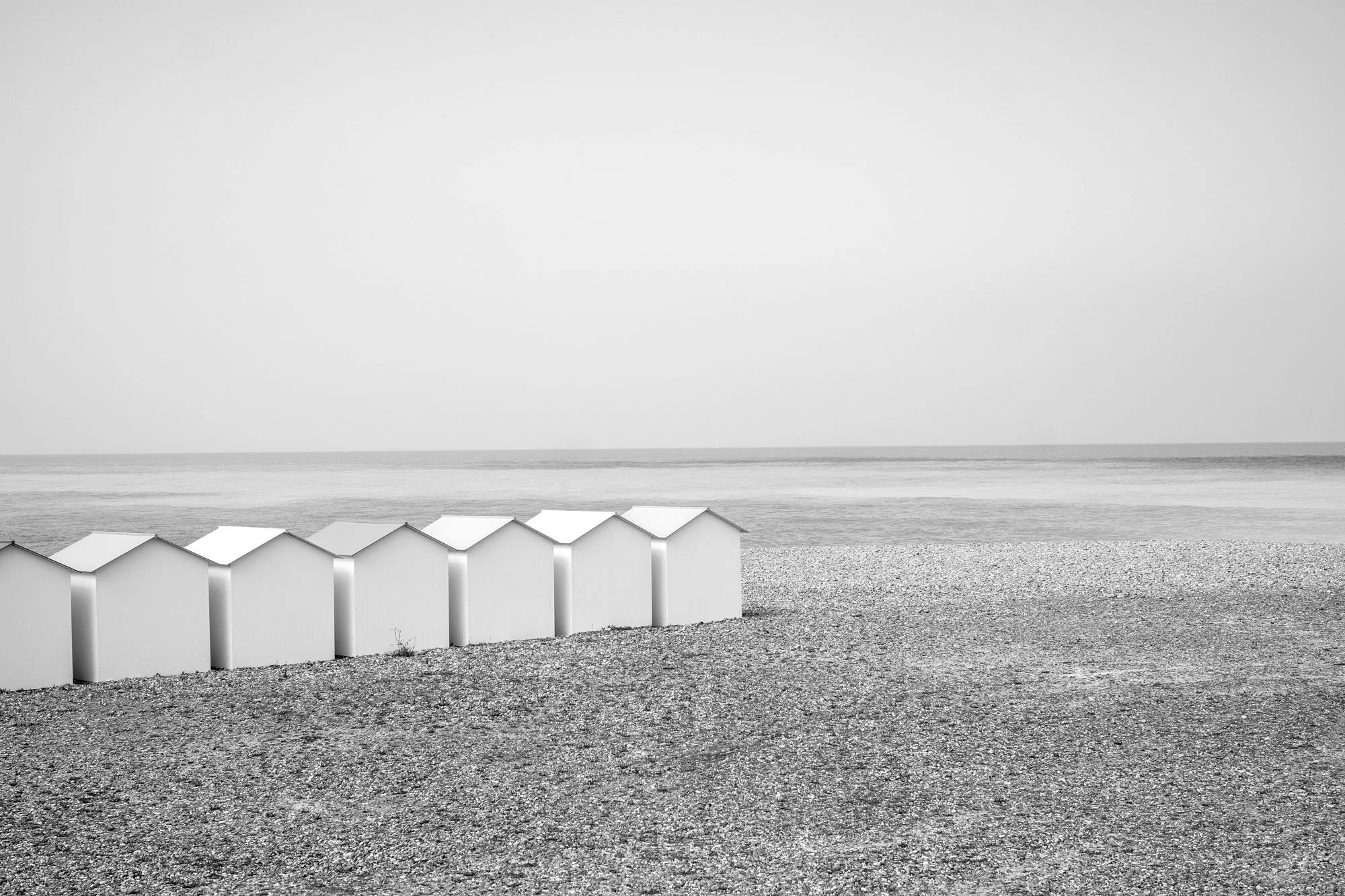  Row of beach huts on the beach at Le Tréport, Normandy. Black-and-white photograph by Chris Perona. 