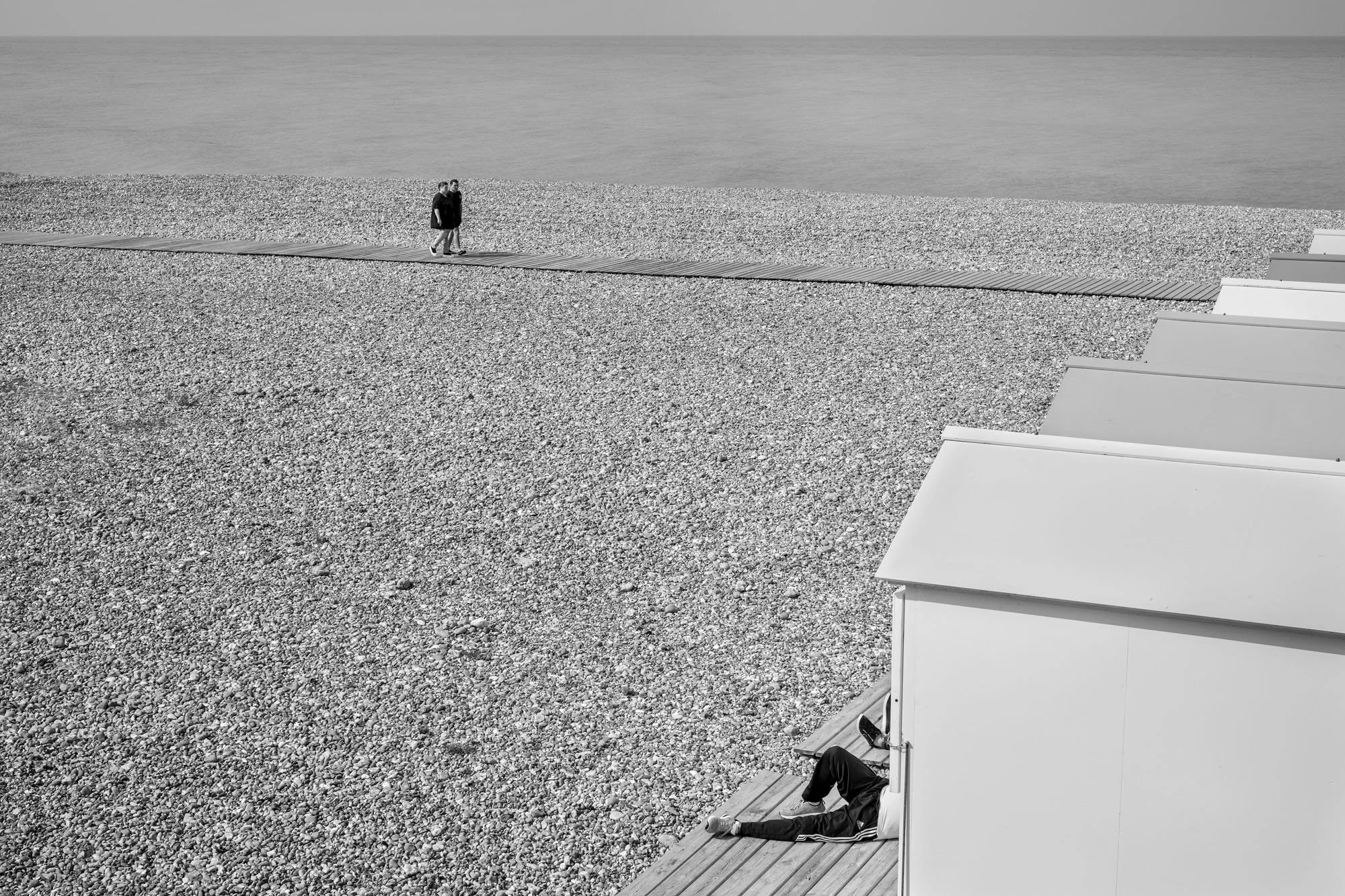  Black-and-white seaside photograph on the beach at Le Tréport, two guys walking, two resting, Normandy, by Chris Perona. 