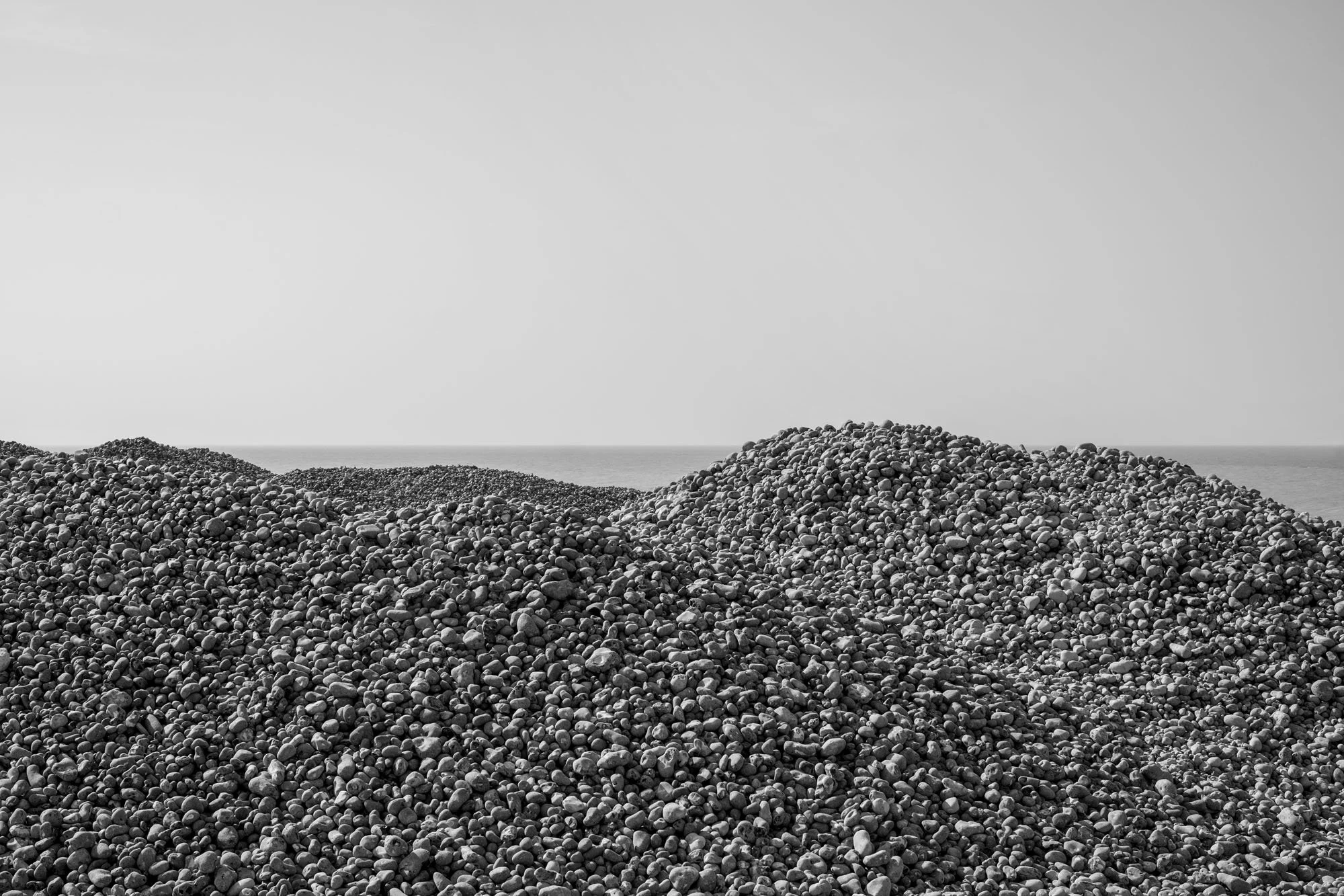  Black-and-white seaside photograph on the beach at Le Tréport, Normandy, pebbles mountain hiding the sea, by Chris Perona. 