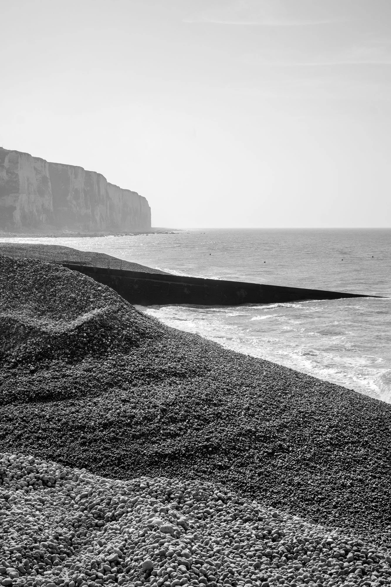  Black-and-white seaside photograph on the beach at Le Tréport, Normandy, pebbles’ dunes forming a graphic image, by Chris Perona. 
