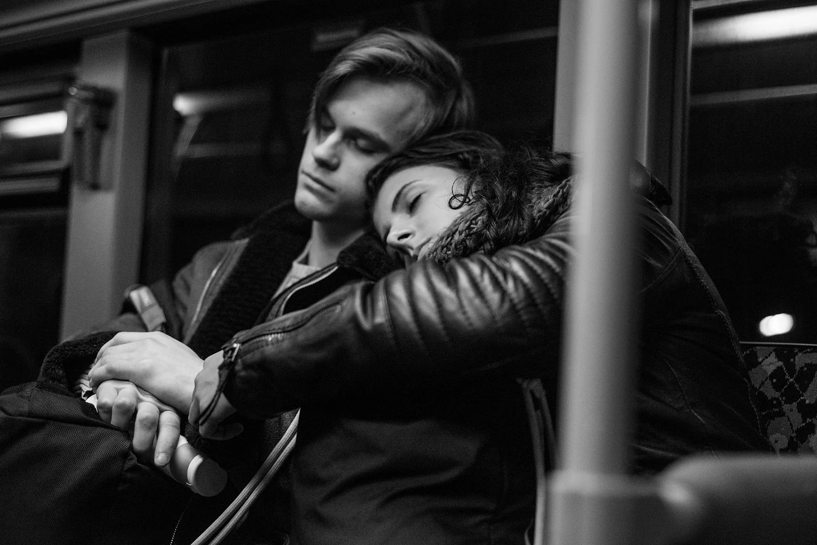  Young couple on a night train, she rests her head on his shoulder, Berlin. Candid street portrait by Chris Perona. 