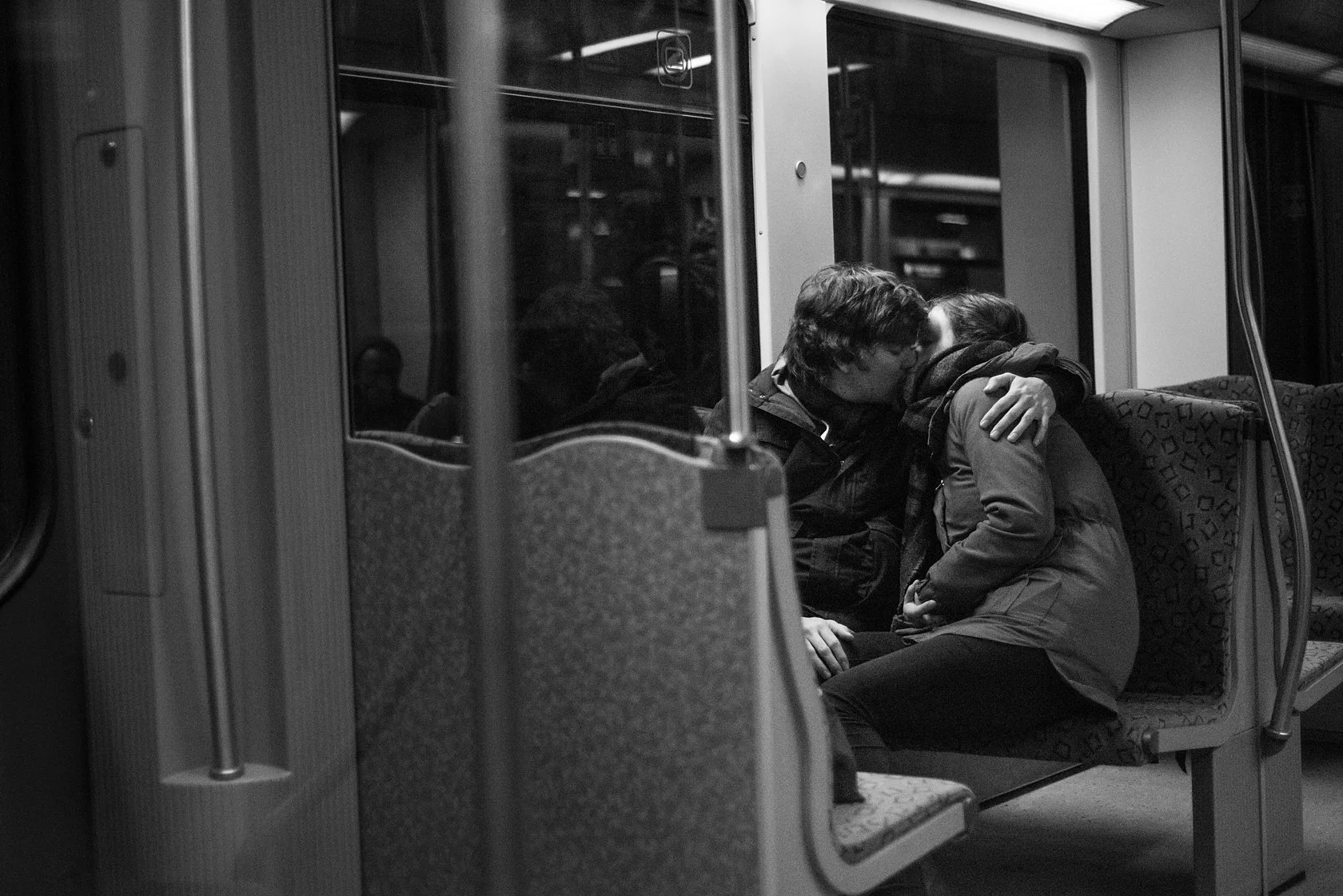  Young couple embracing in an empty S-Bahn carriage at night, Berlin. Candid street portrait by Chris Perona. 