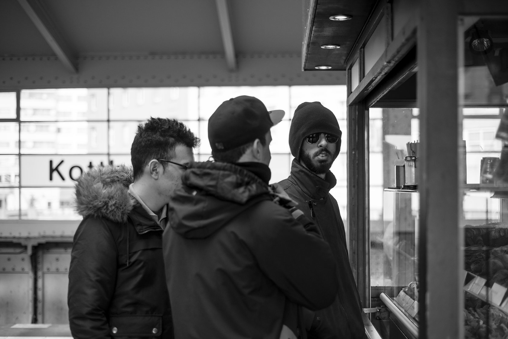  Three young men waiting on the platform at Kottbusser Tor station, Berlin. Candid street portrait by Chris Perona. 