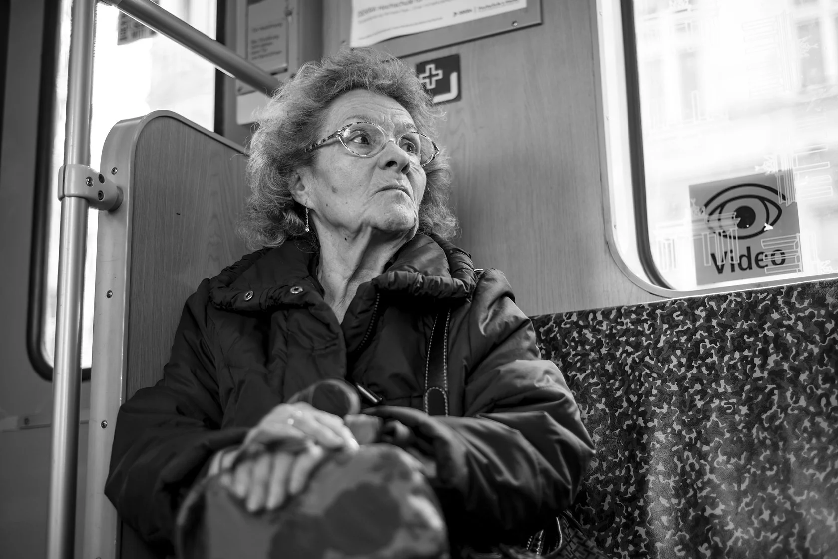  Elderly woman with glasses seated on a Berlin S-Bahn, looking out. Candid street portrait by Chris Perona. 