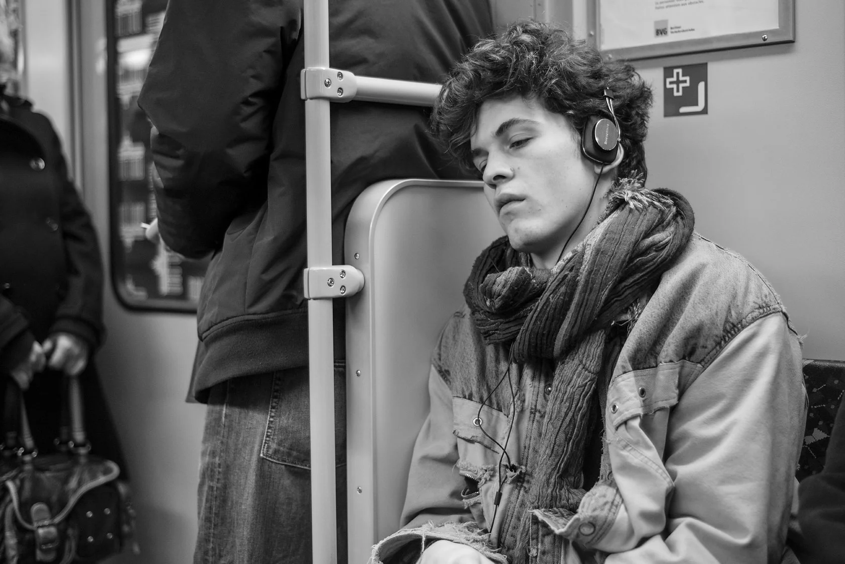  Young man with curly hair and headphones dozing on a Berlin train. Candid street portrait by Chris Perona. 
