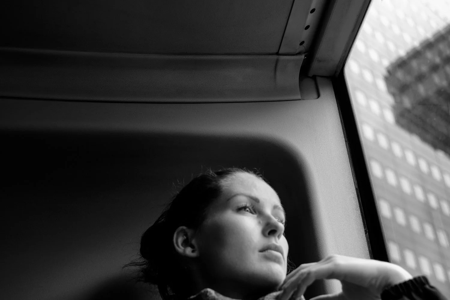  Woman gazing out of a tram window in soft light, Berlin. Candid street portrait by Chris Perona. 