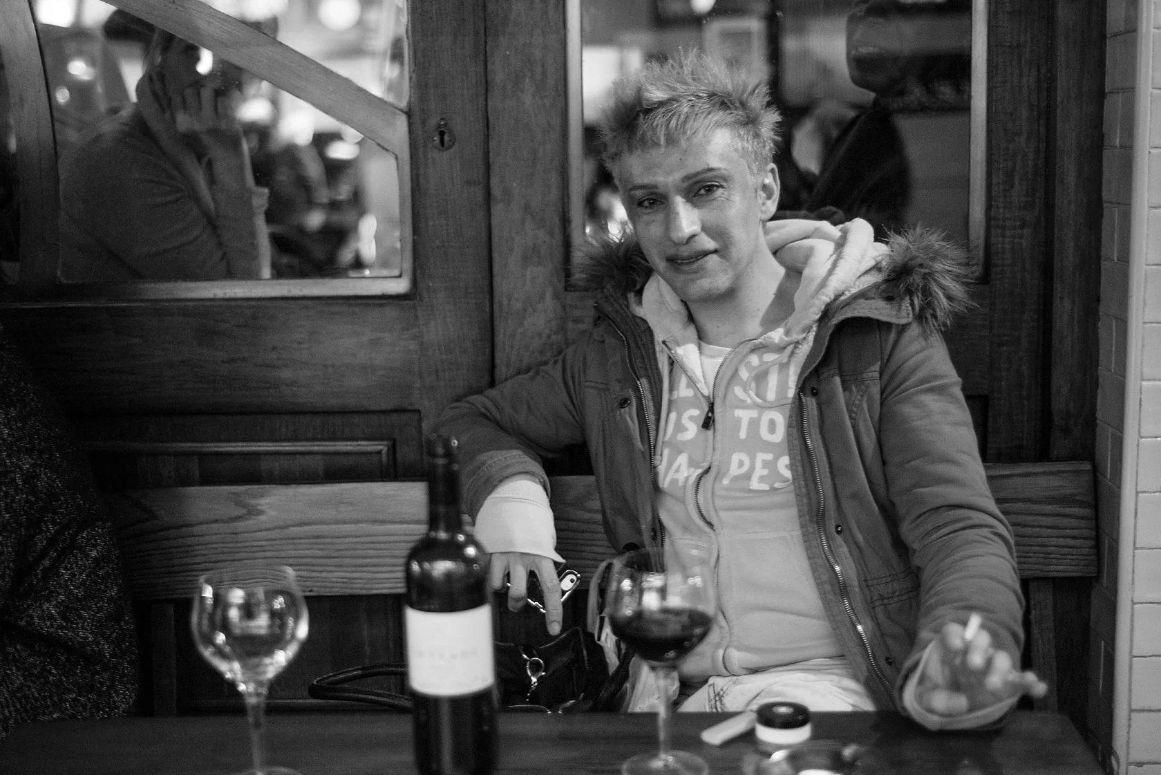  Young man with a glass of red wine at a pub table, London. Candid street portrait by Chris Perona. 