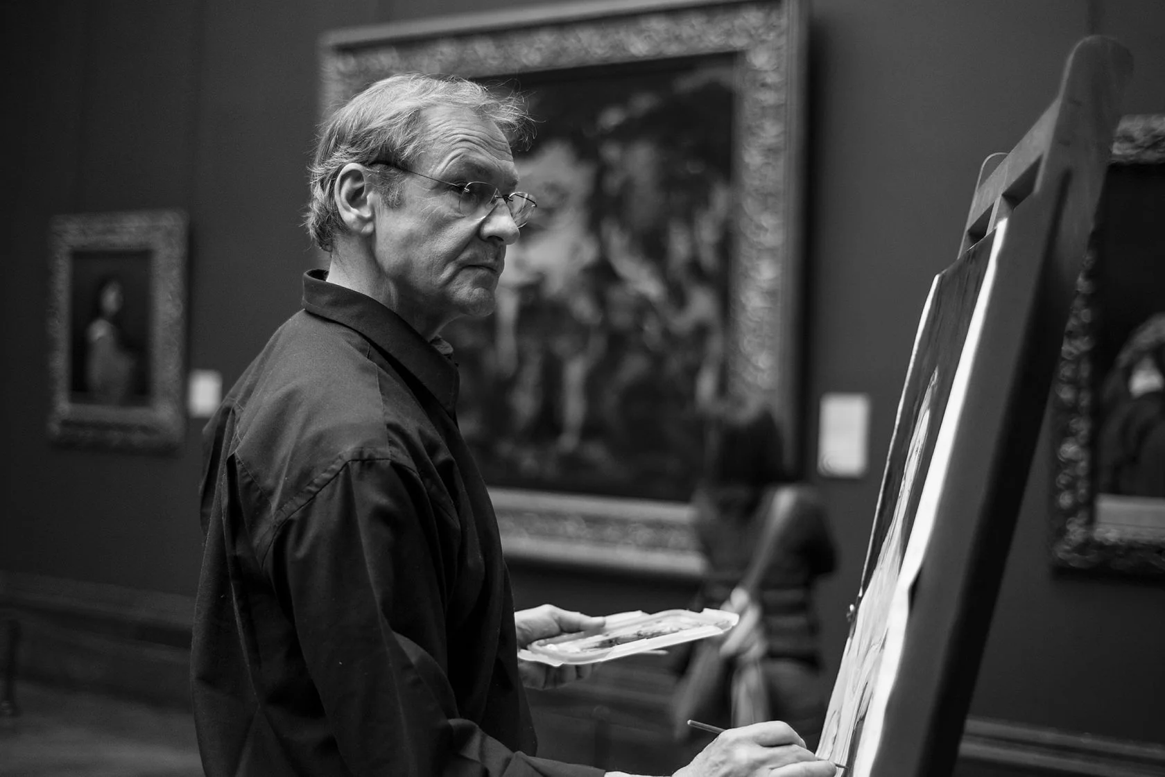  Older man copying a painting at an easel in a museum gallery, London. Candid street portrait by Chris Perona. 