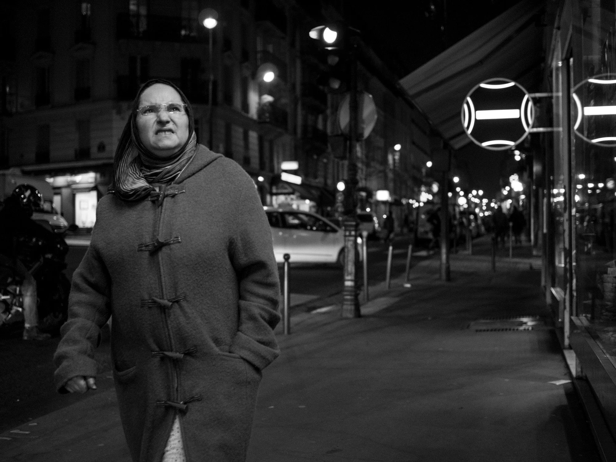  Woman in a duffle coat walking down a Paris street at night. Candid street portrait by Chris Perona. 
