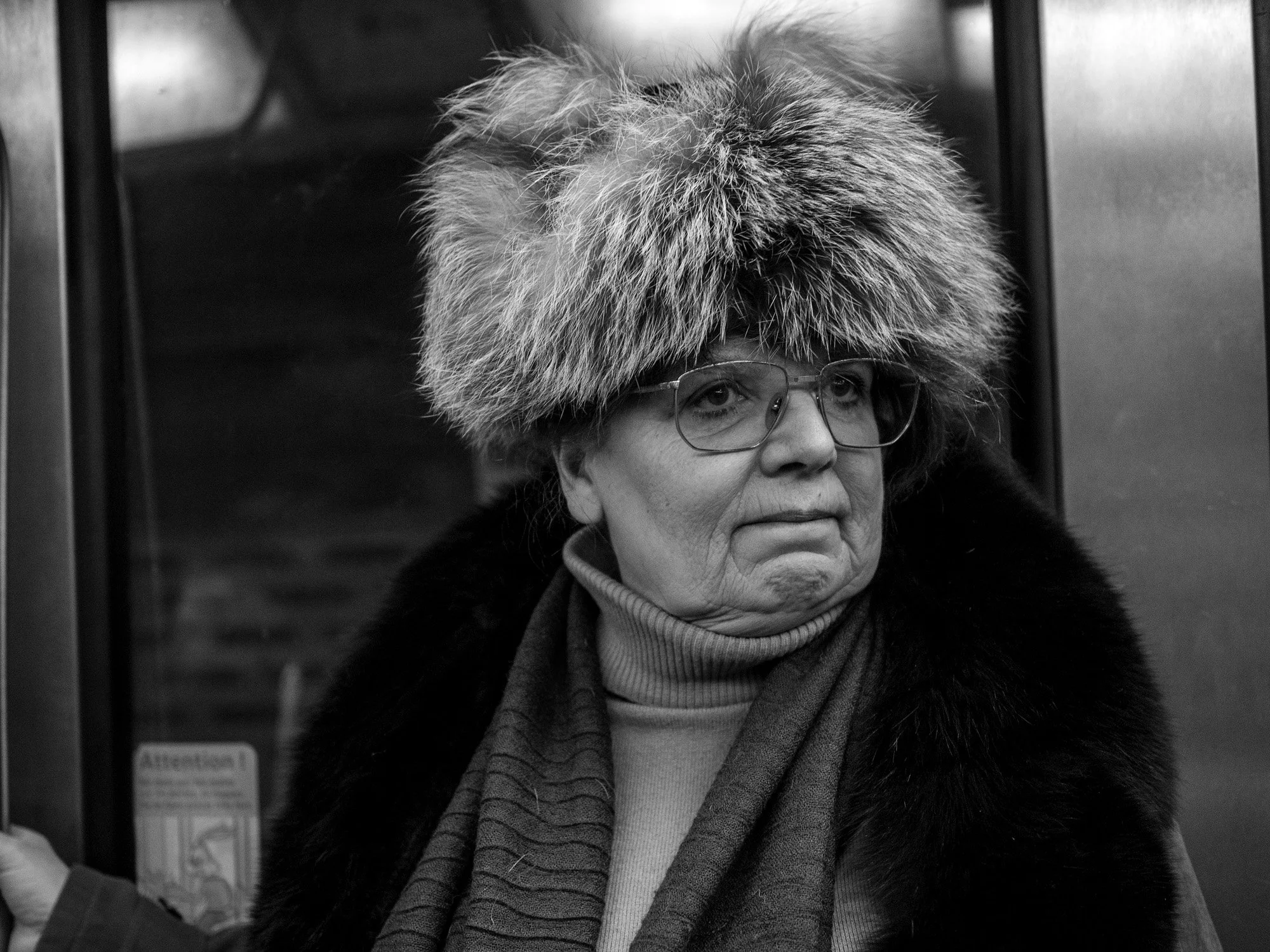  Older woman in a large fur hat and glasses in the Paris metro. Candid street portrait by Chris Perona. 