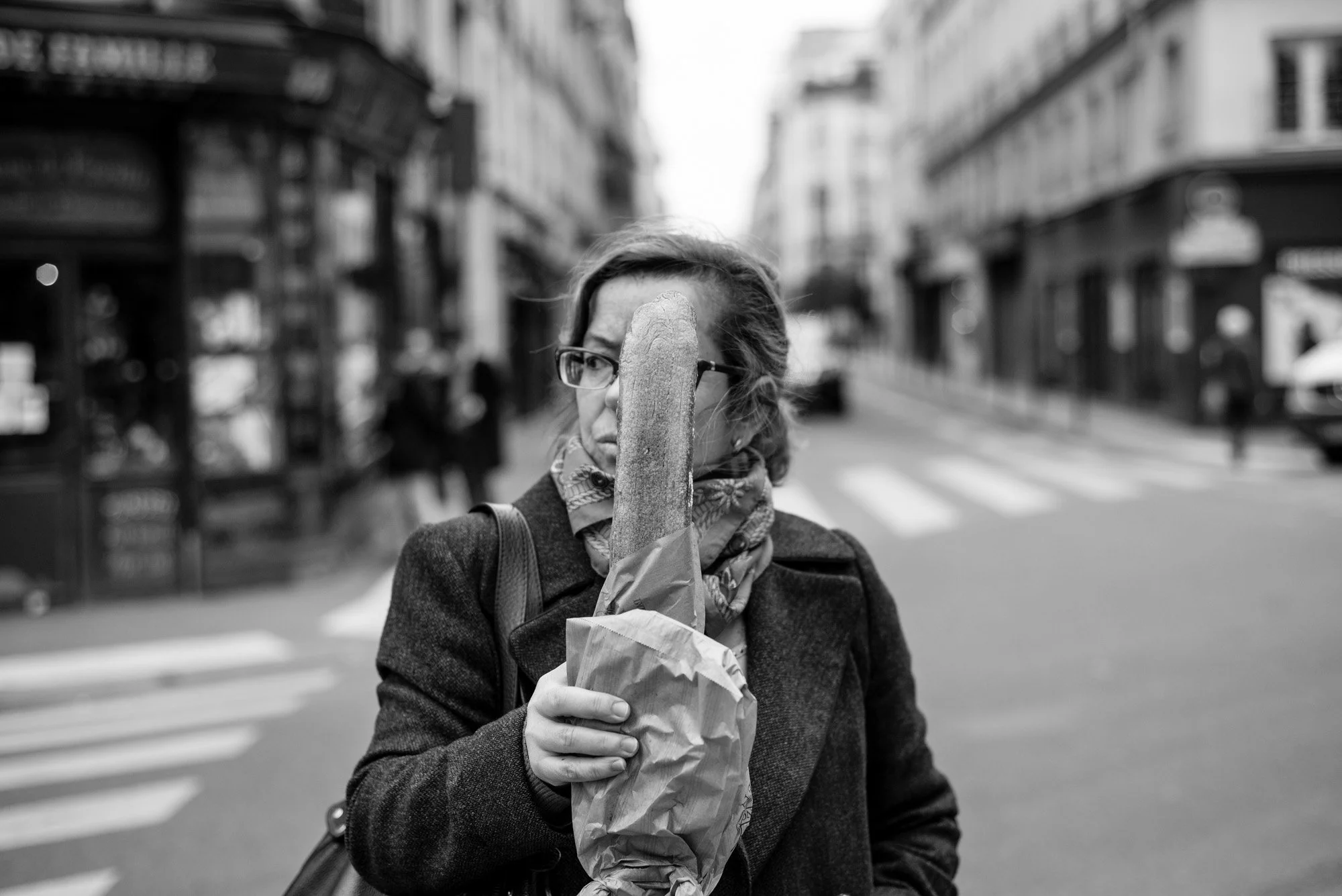  Woman carrying baguettes in a paper bag on a Paris street. Candid street portrait by Chris Perona. 