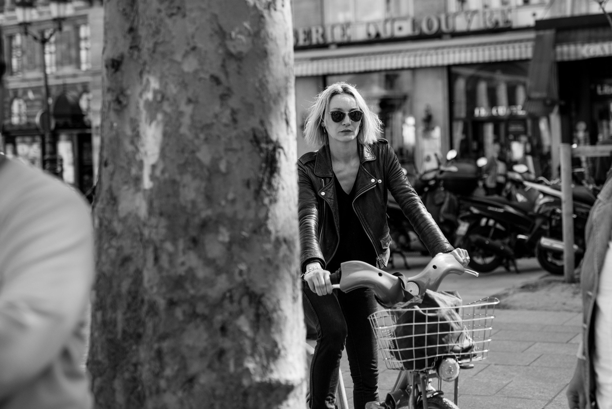  Woman in sunglasses cycling past a plane tree, Paris. Candid street portrait by Chris Perona. 