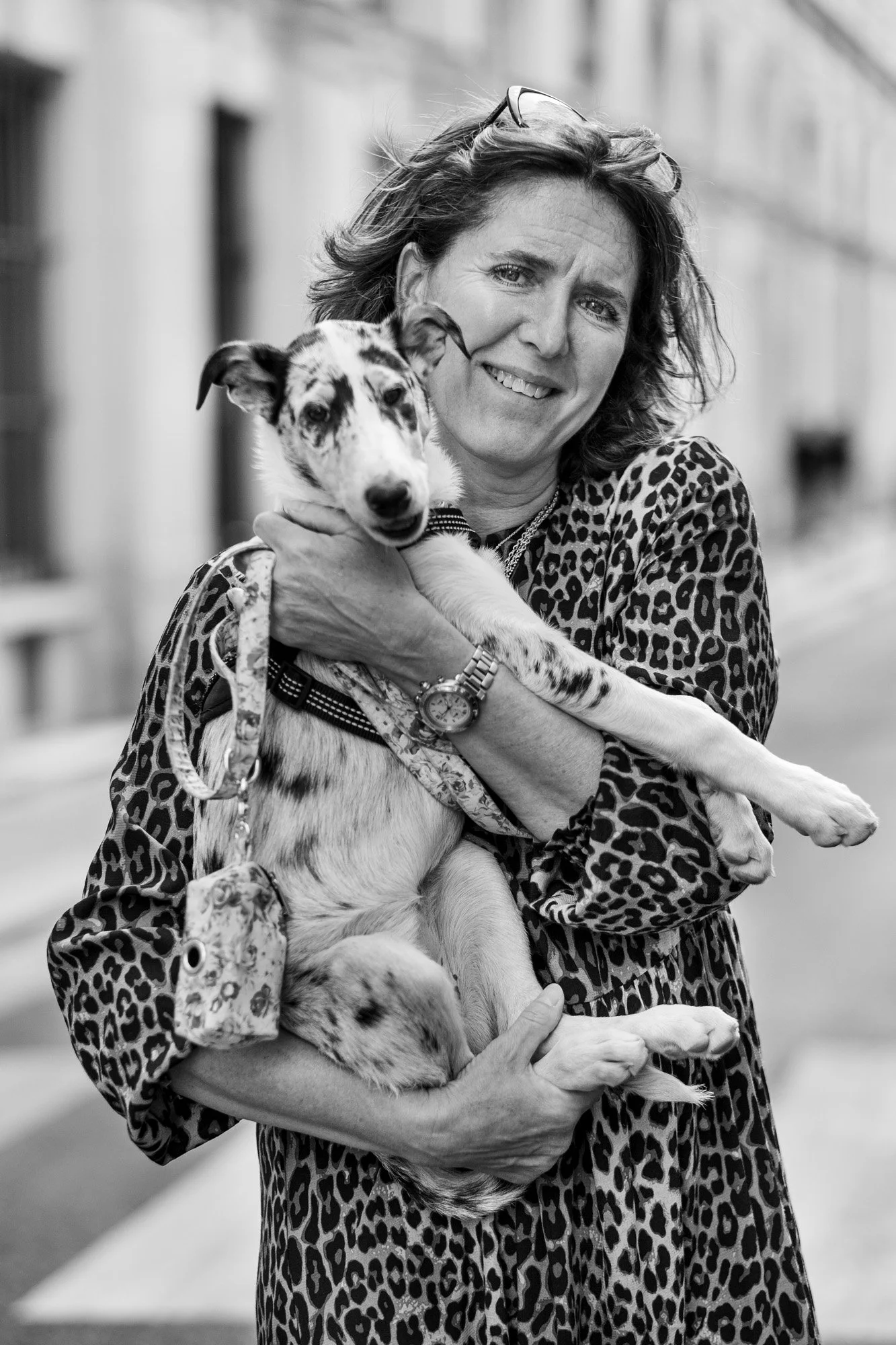  Smiling woman in a leopard-print dress holding her dog, Paris. Street portrait by Chris Perona. 