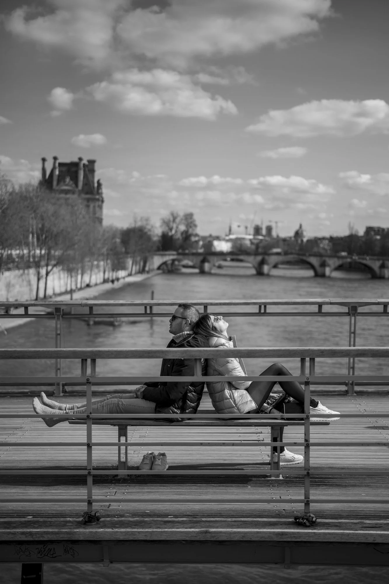  Couple relaxing on a bench on the Pont des Arts above the Seine, Paris. Candid street portrait by Chris Perona. 