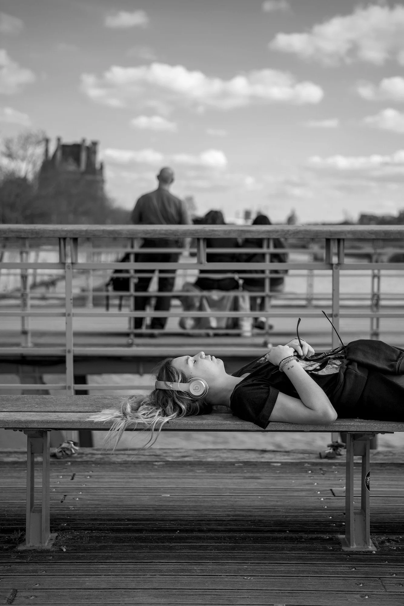  Woman lying on a bench in the sun on the Pont des Arts, Paris. Candid street portrait by Chris Perona. 