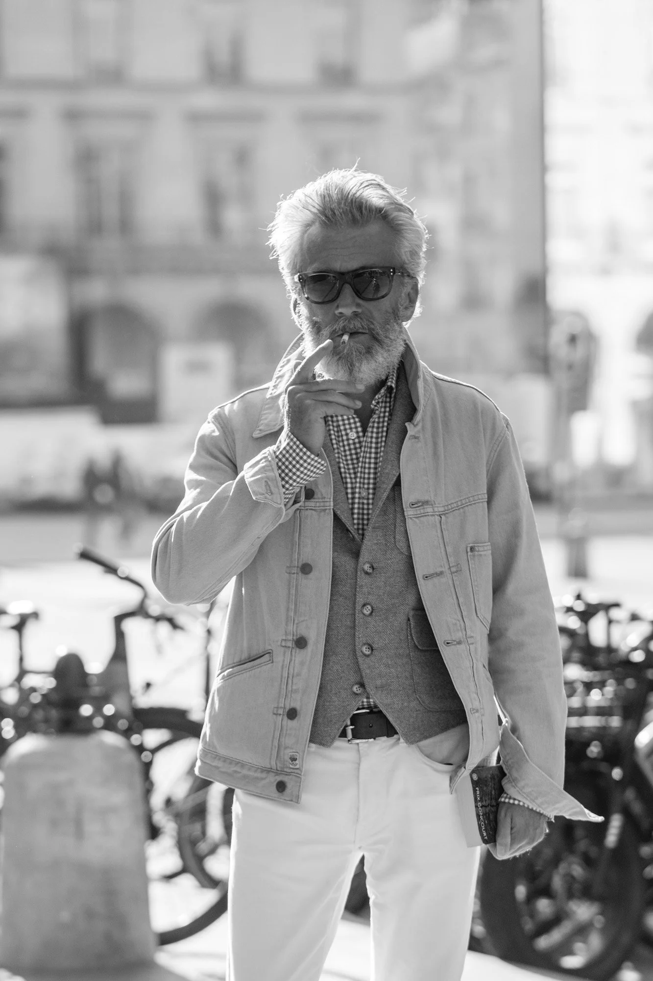  Stylish grey-haired man in sunglasses and a light jacket, smoking on a Paris street. Street portrait by Chris Perona. 