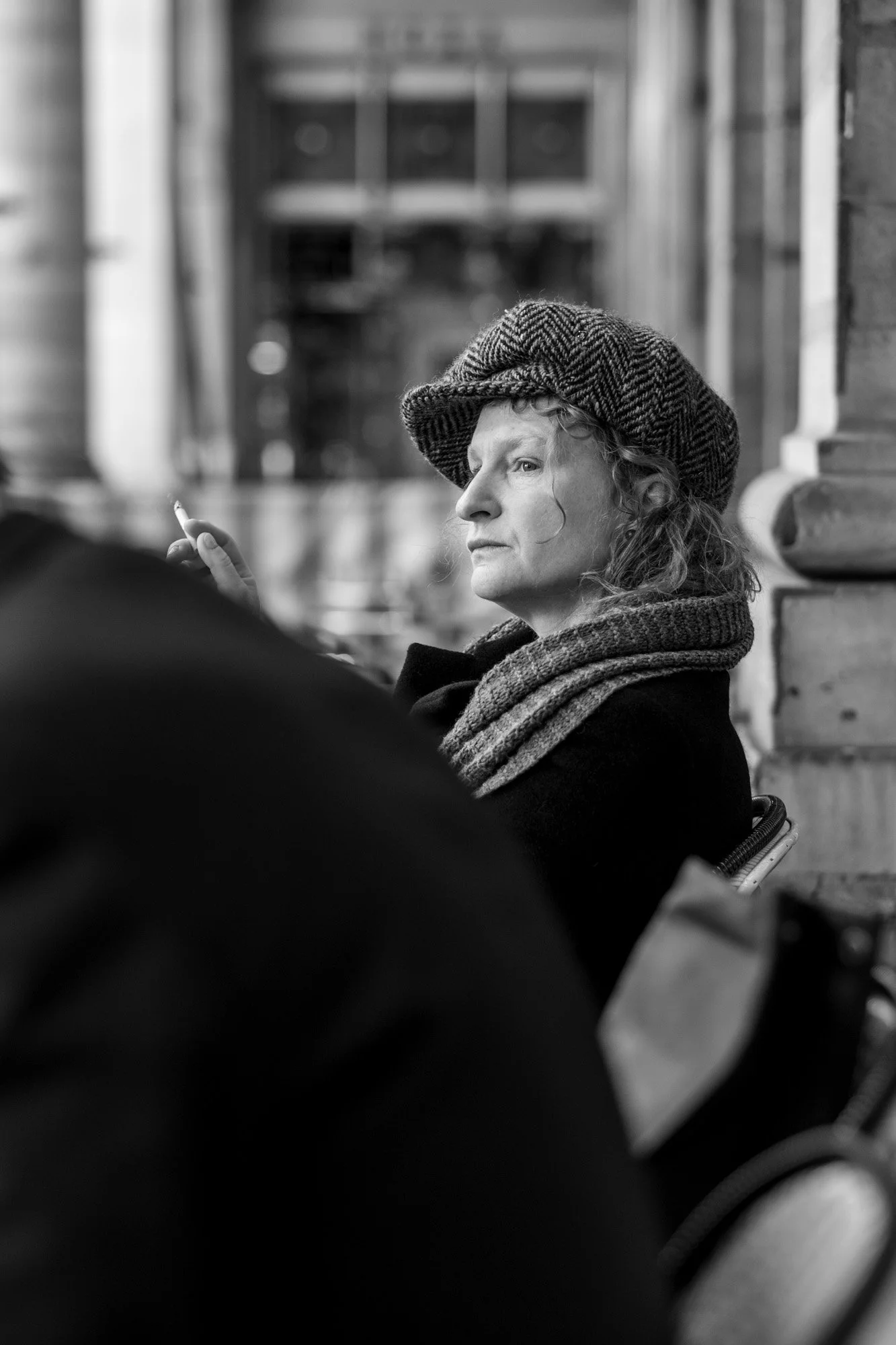  Older woman in a cap and scarf gazing into the distance, Paris. Candid street portrait by Chris Perona. 