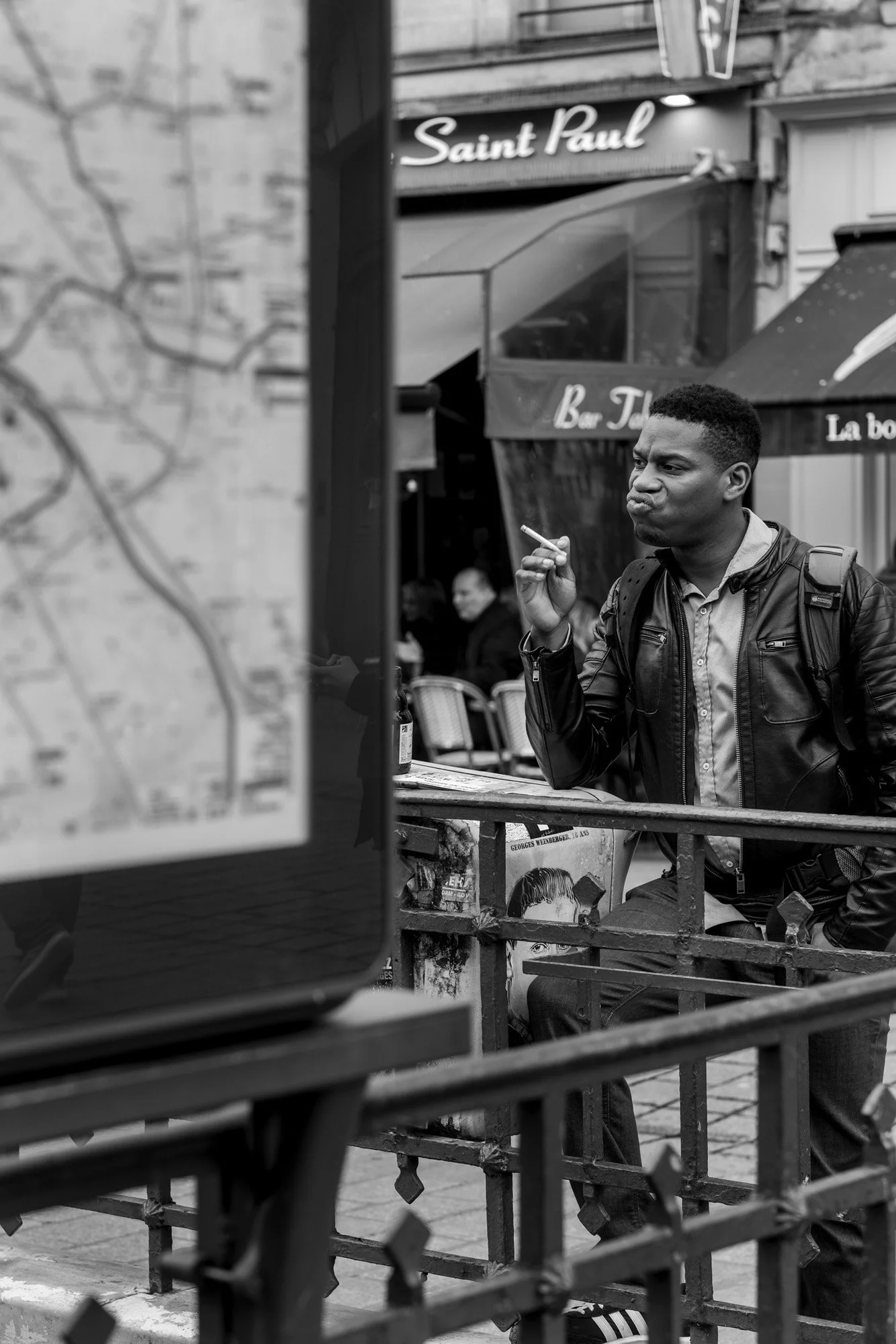  Young man gesturing by a metro entrance near Saint-Paul, Paris. Candid street portrait by Chris Perona. 