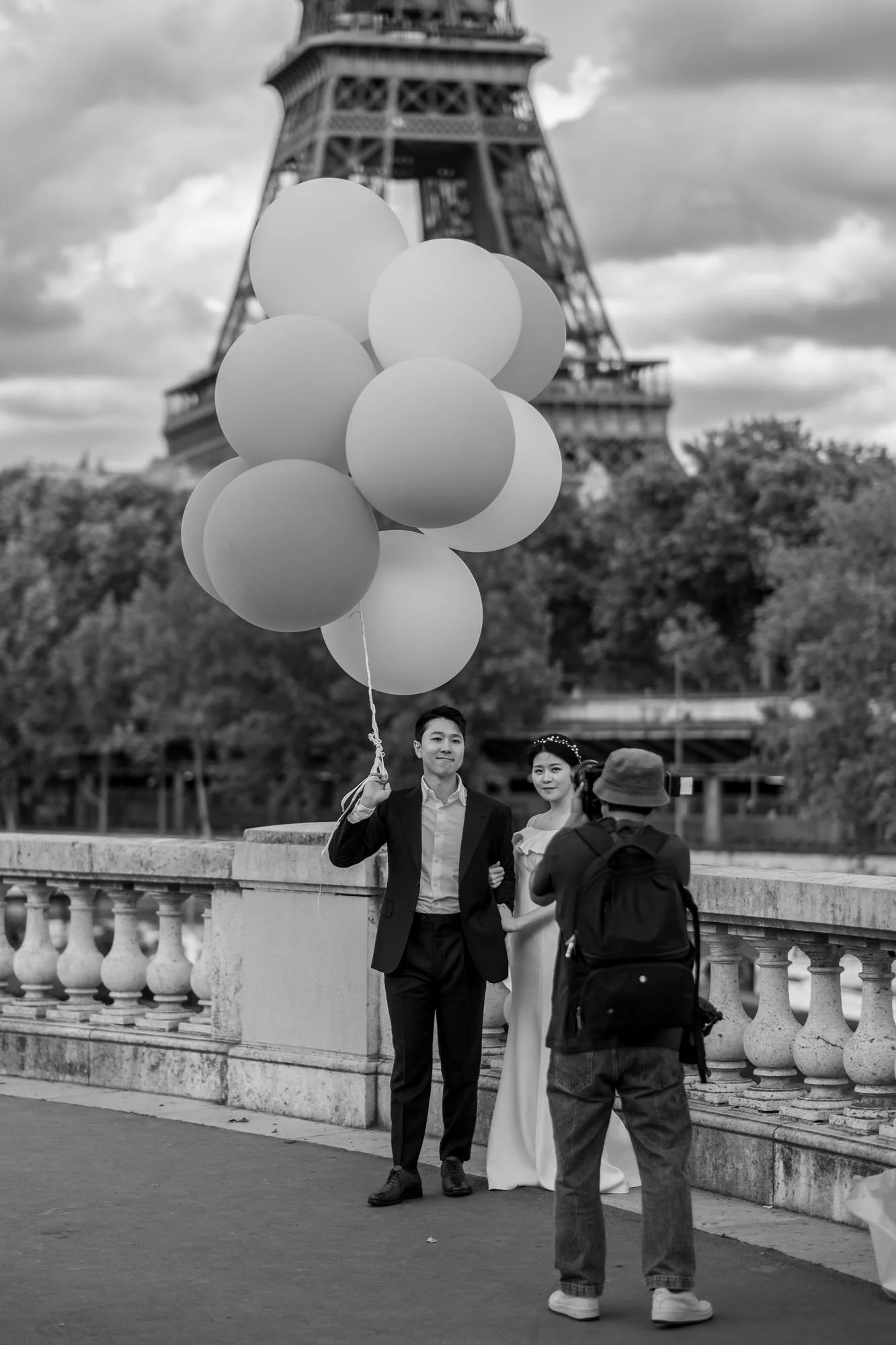  Couple with a bunch of balloons being photographed before the Eiffel Tower, Pont de Bir-Hakeim, Paris. Street photograph by Chris Perona. 