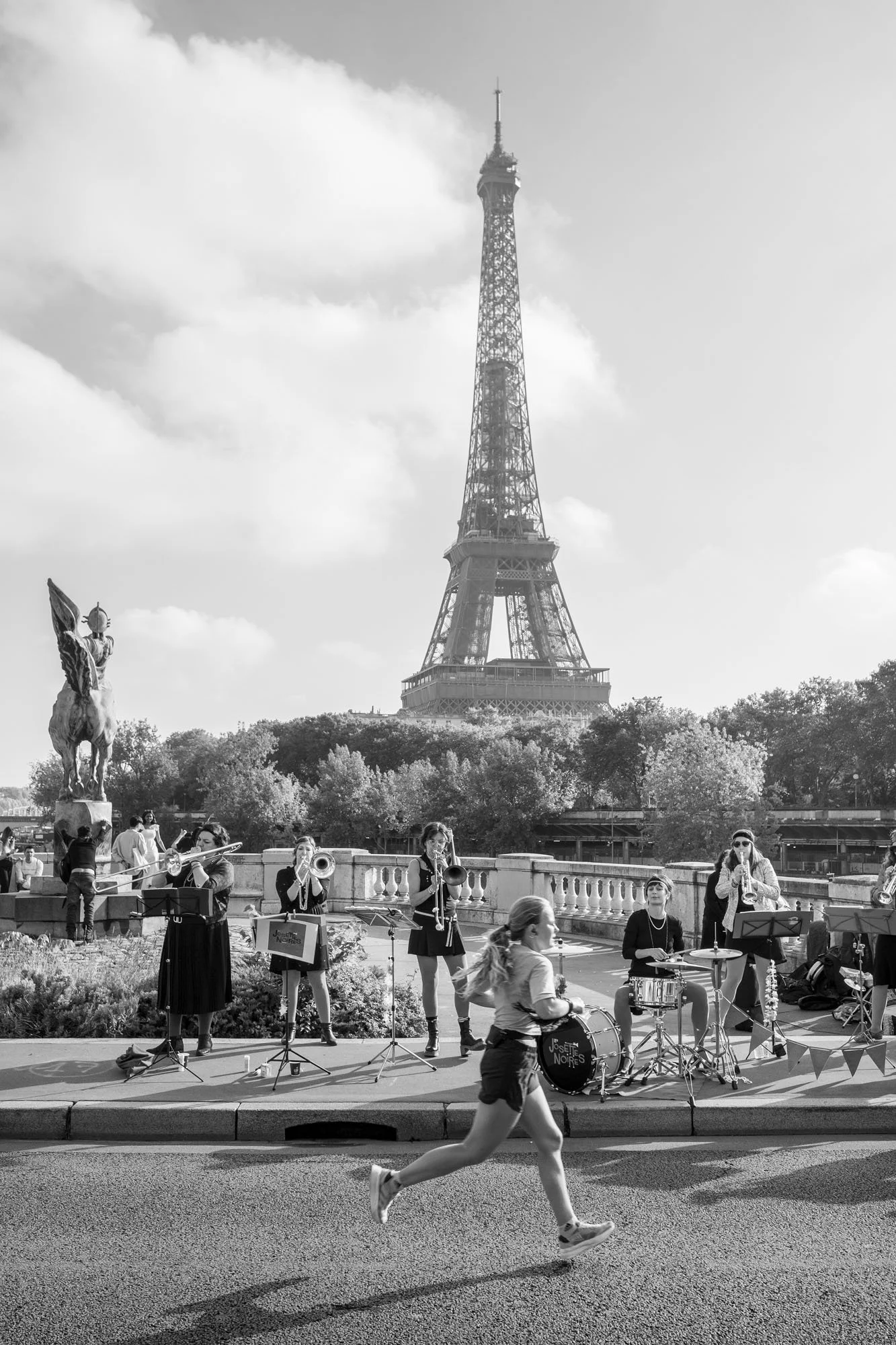  Paris Marathon: a runner passes while a women’s band plays, Pont de Bir-Hakeim, Paris. Street photograph by Chris Perona. 
