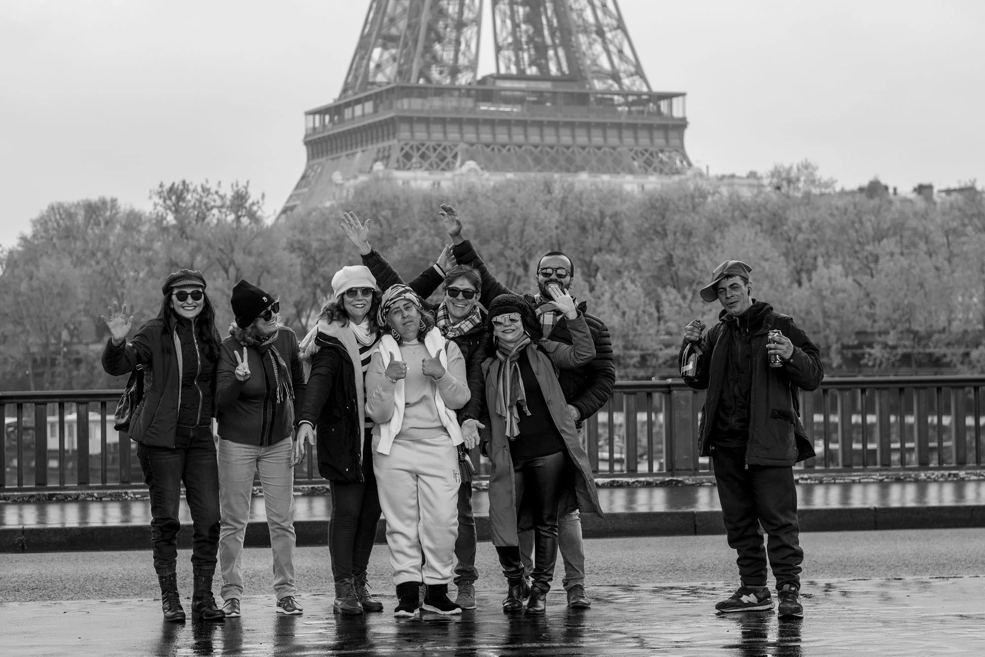  Group of friends posing for a photo with the Eiffel Tower behind, Pont de Bir-Hakeim, Paris. Street photograph by Chris Perona. 