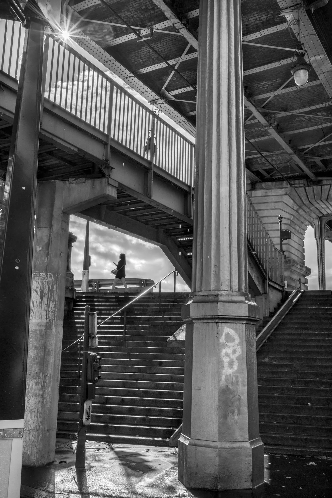  Iron staircase and columns beneath the metro viaduct in sunlight, Pont de Bir-Hakeim, Paris. Architecture photograph by Chris Perona. 