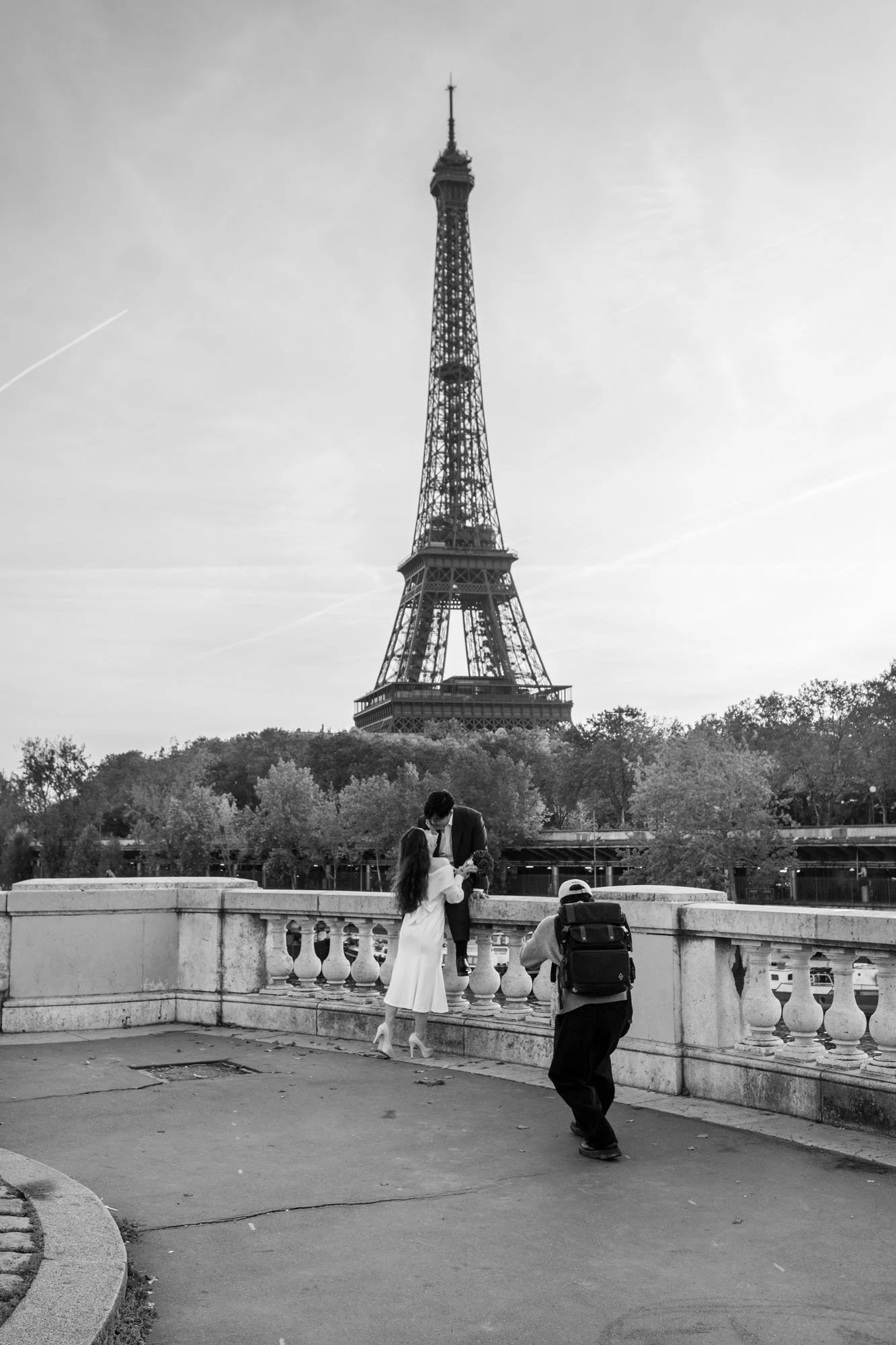  Couple kissing at the balustrade while a photographer captures them, Pont de Bir-Hakeim, Paris. Street photograph by Chris Perona. 