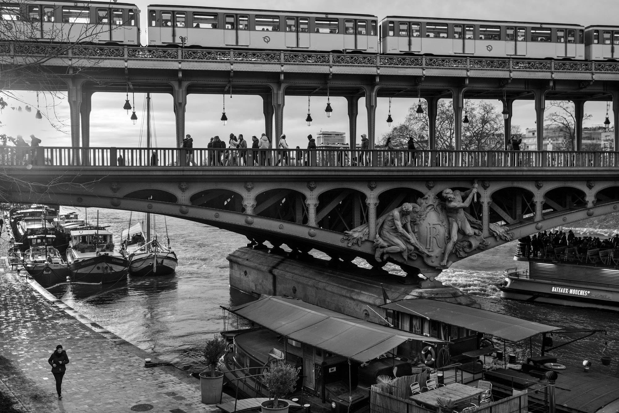  Metro train crossing the bridge above moored barges, seen from the riverbank, Pont de Bir-Hakeim, Paris. Photograph by Chris Perona. 