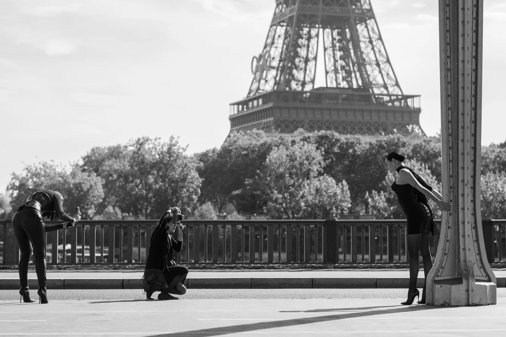  Photographers at work with their subjects along the balustrade, beneath the Eiffel Tower, Pont de Bir-Hakeim, Paris. Street photograph by Chris Perona. 