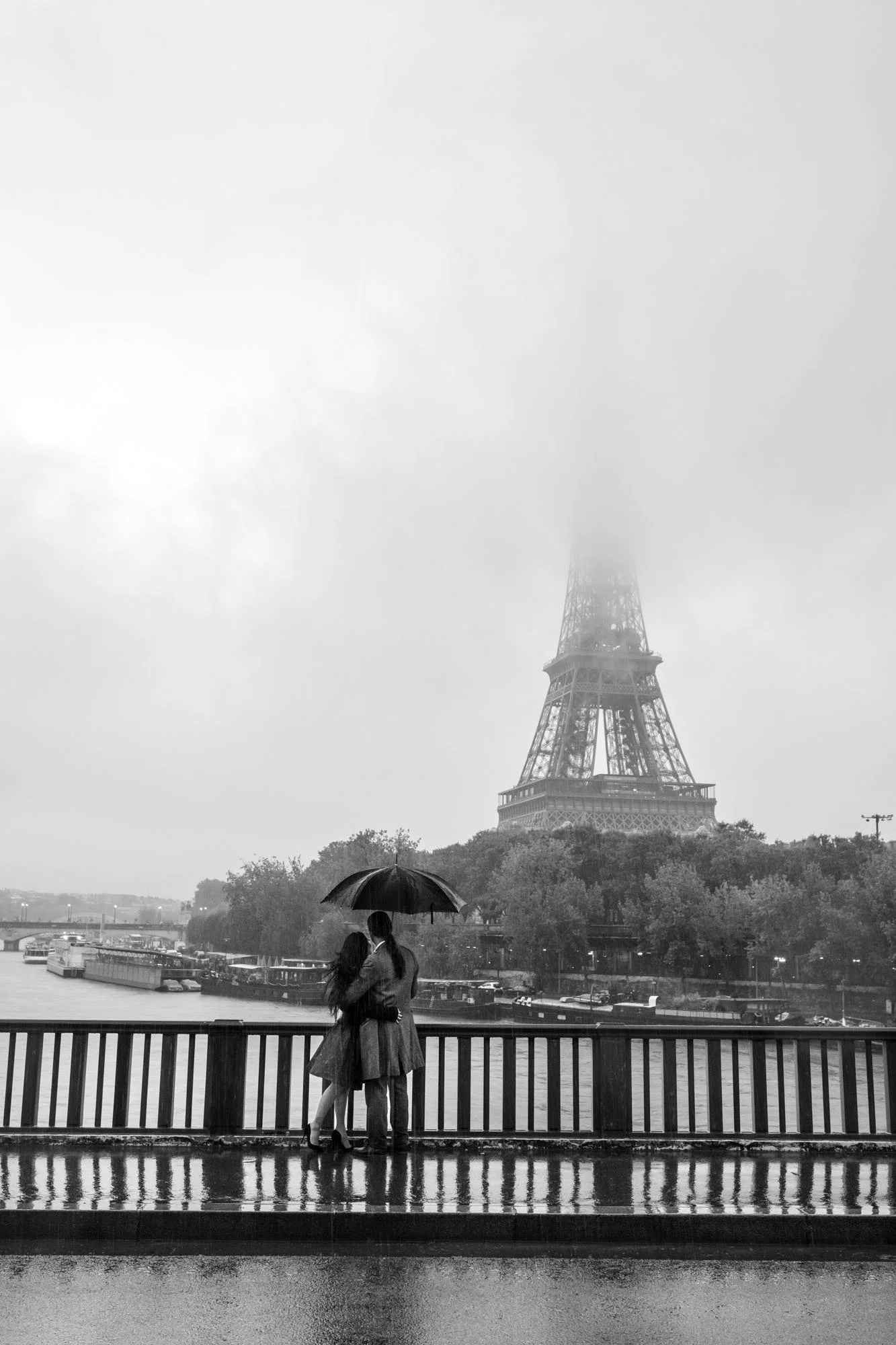  Person with an umbrella at the railing, the Eiffel Tower fading into fog, Pont de Bir-Hakeim, Paris. Street photograph by Chris Perona. 