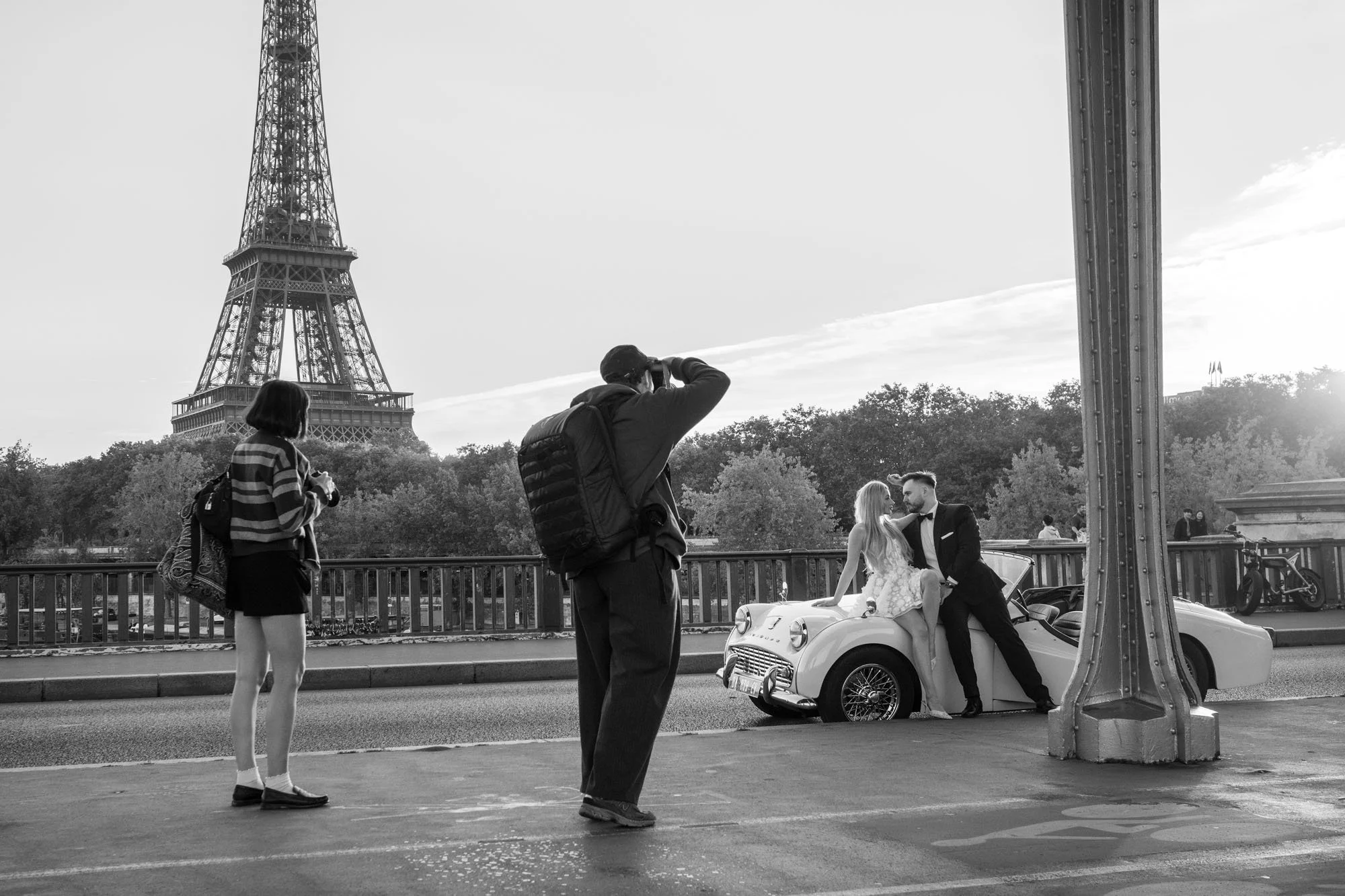  Photographers shooting a bride and groom with a vintage car before the Eiffel Tower, Pont de Bir-Hakeim, Paris. Street photograph by Chris Perona. 