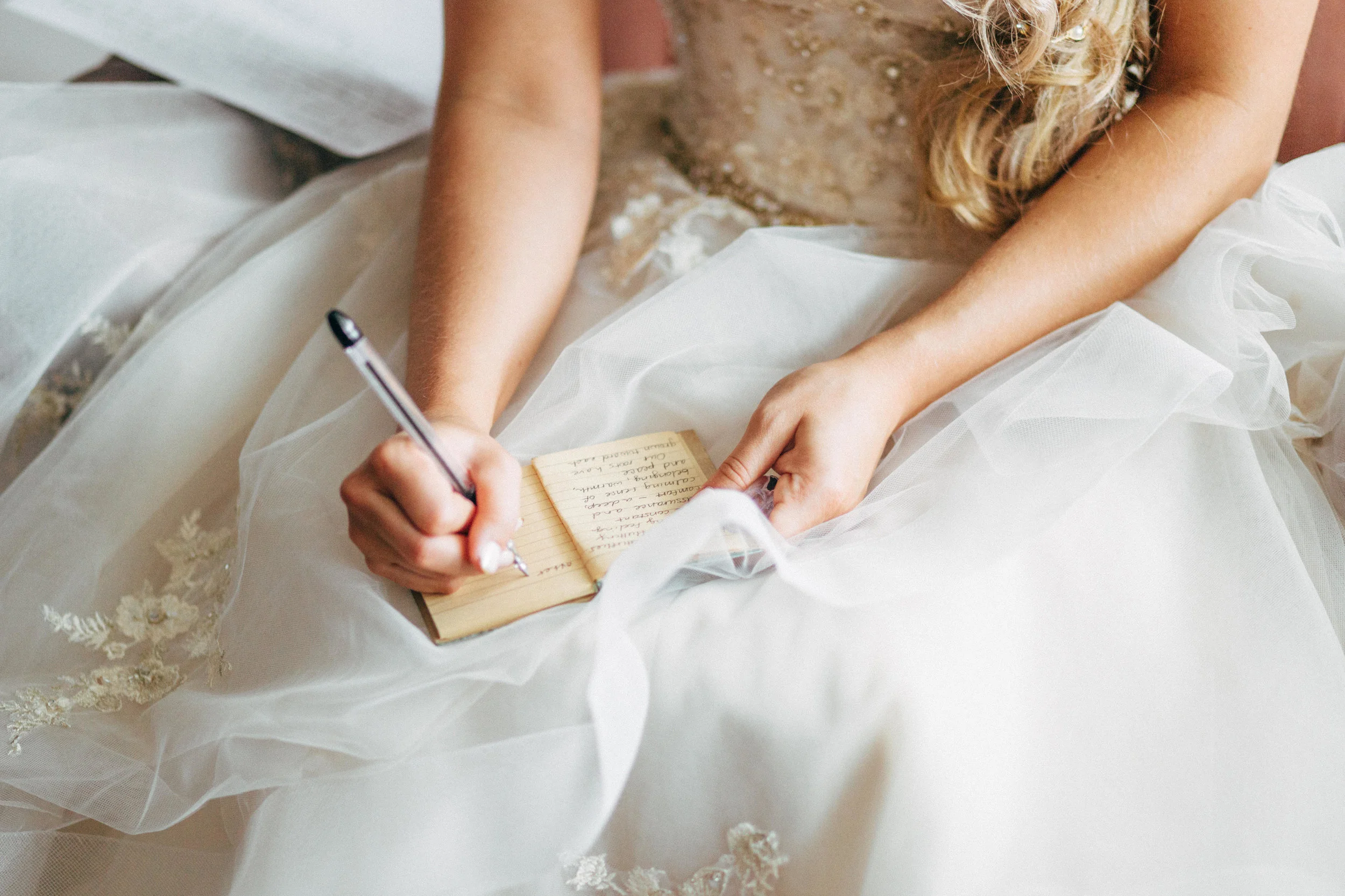 bride in wedding dress writing letter to her groom before wedding