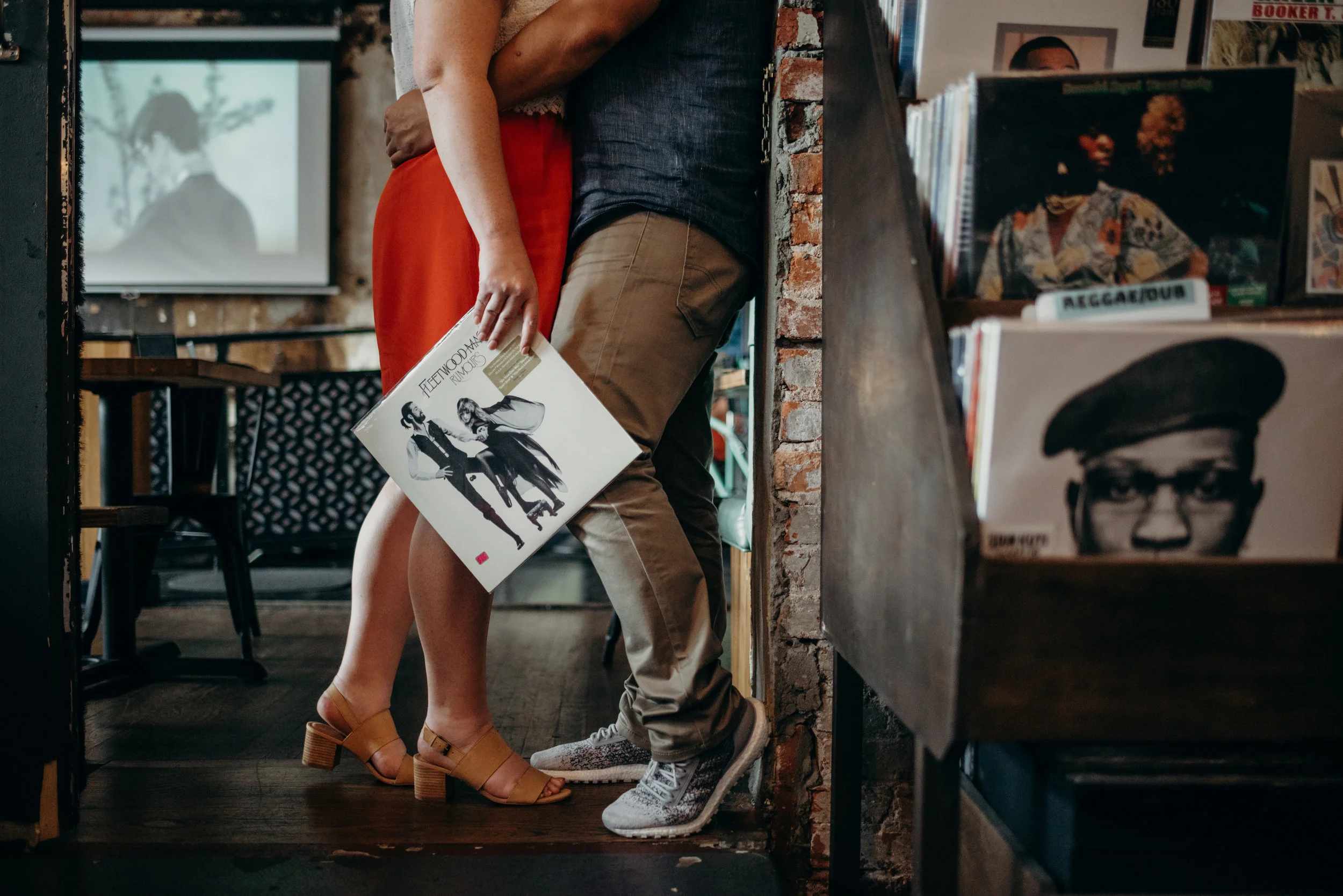 engaged couple embracing with Fleetwood Mac record in their hand