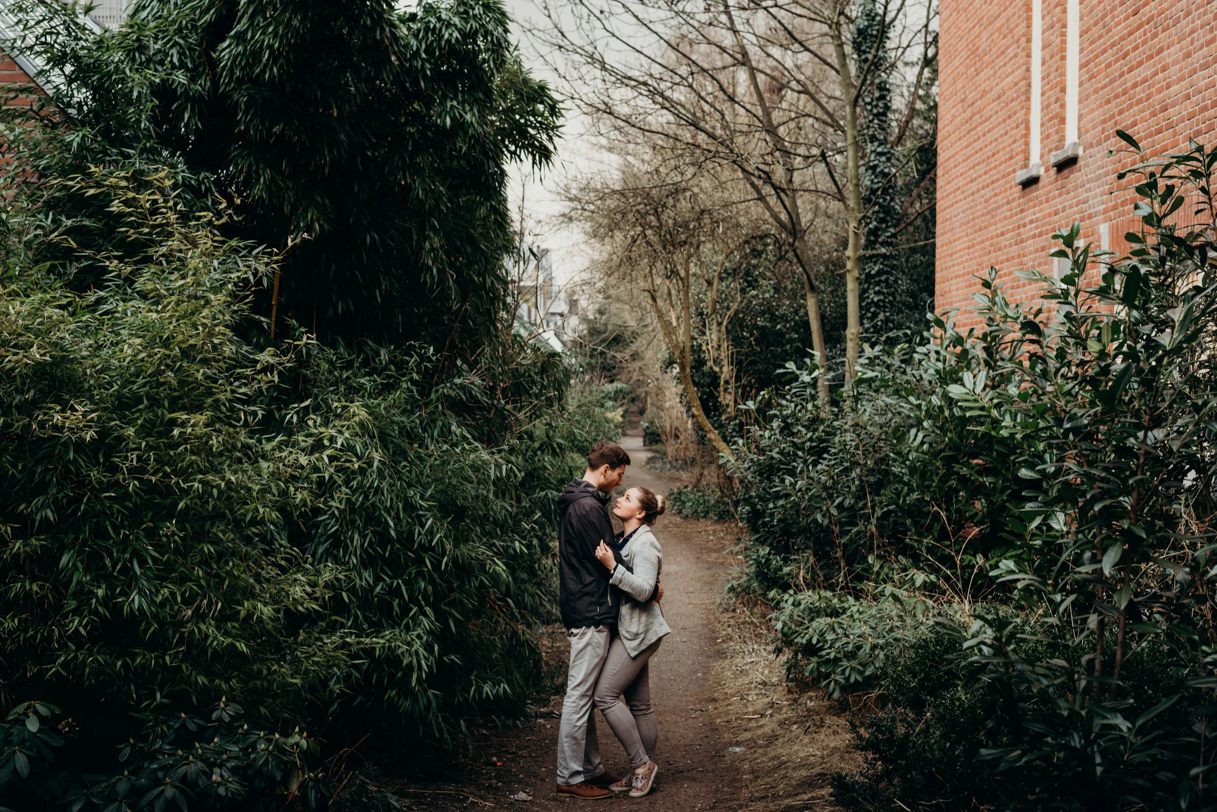 married couple embrace on a path surrounded by trees in Amsterdam